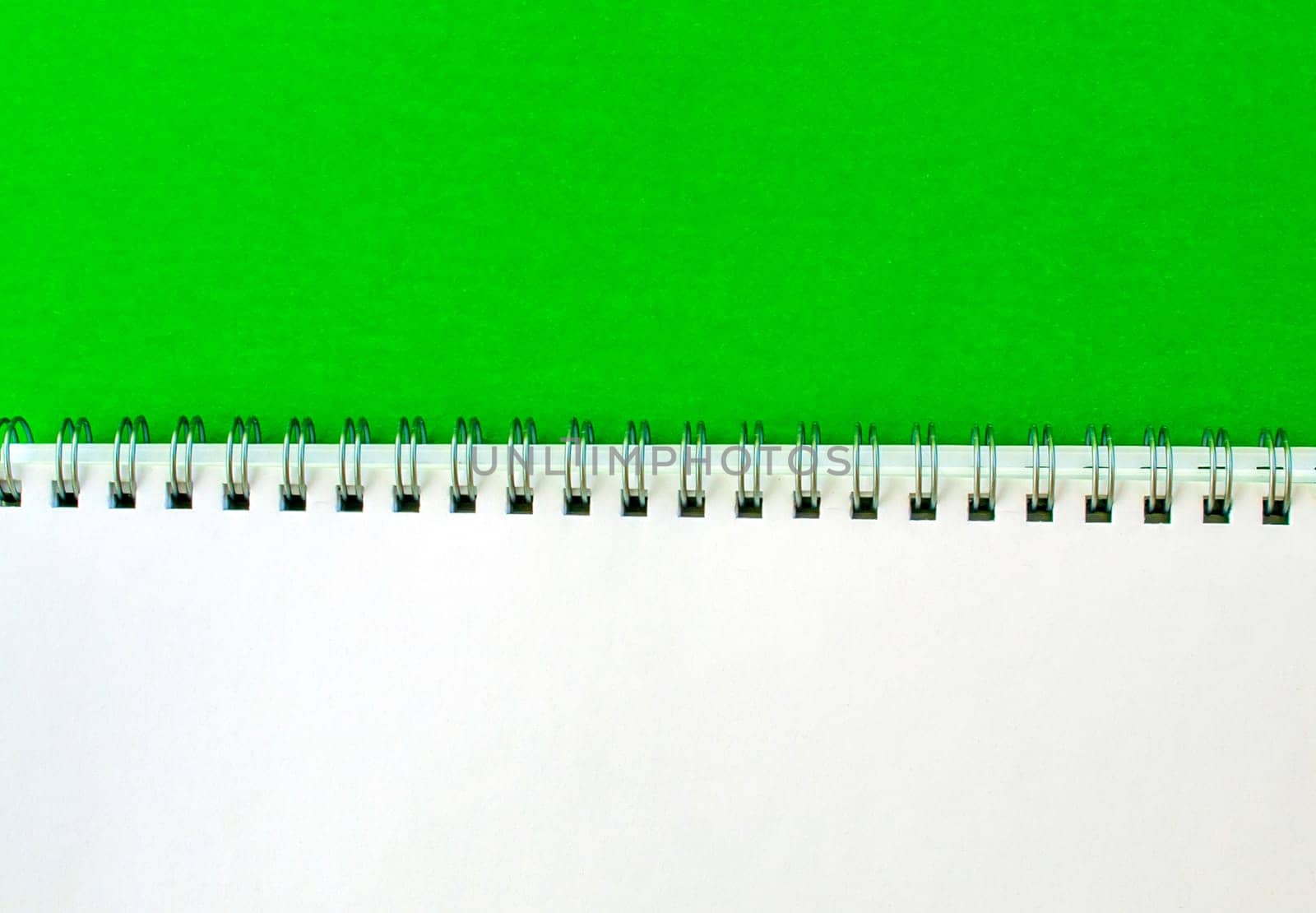 White notepad with a spring on a green background.
School white notebook.