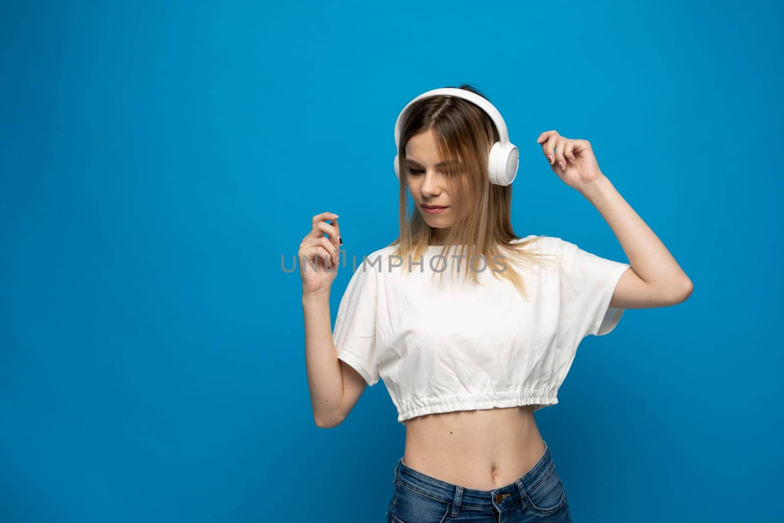Nice attractive pretty dreamy cheerful cheery girl listening to the muisc and having fun isolated on bright blue color background