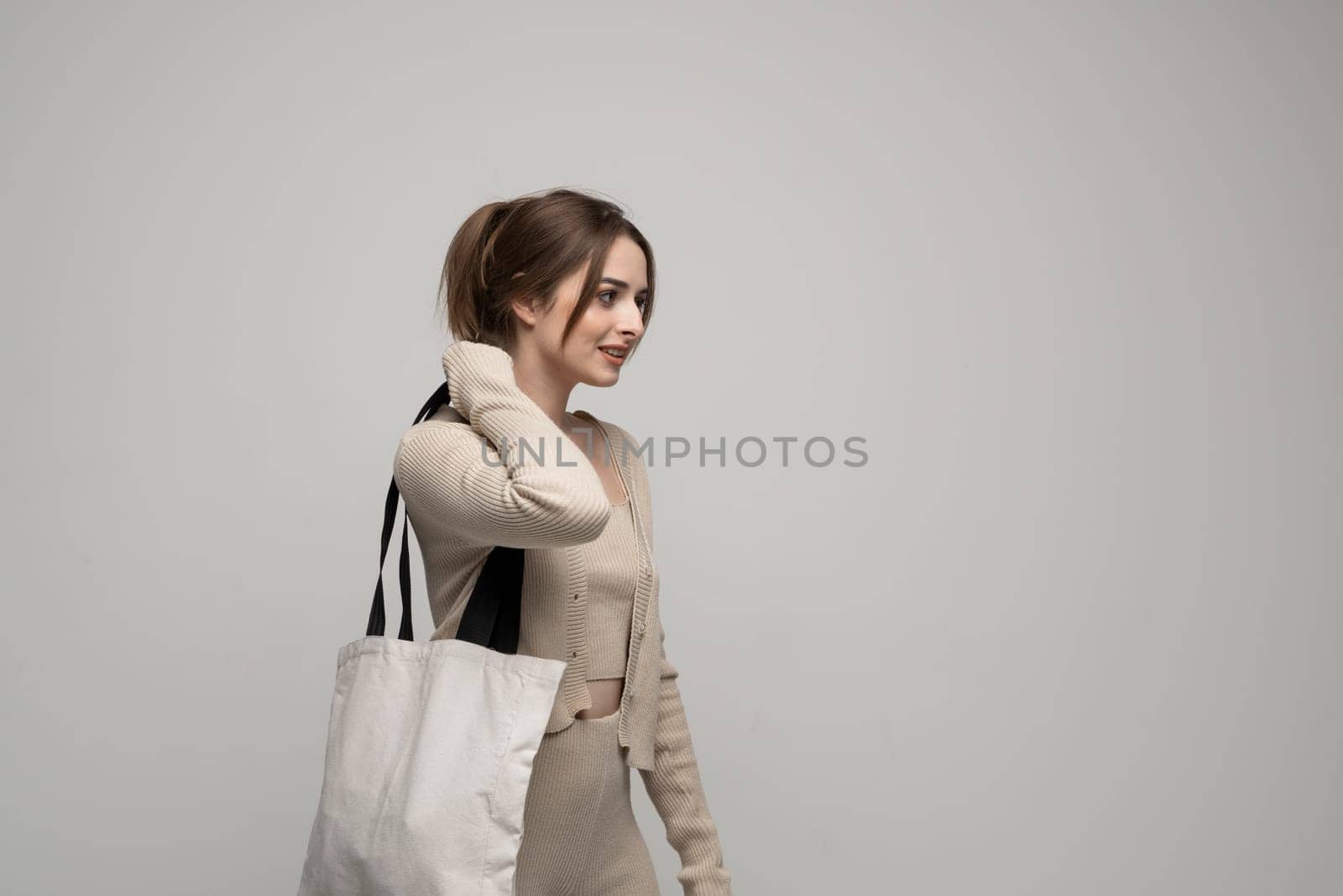 Happy, smiling brunette young woman carrying reusable cotton bag. Concept of recycle for better environment. No plastic