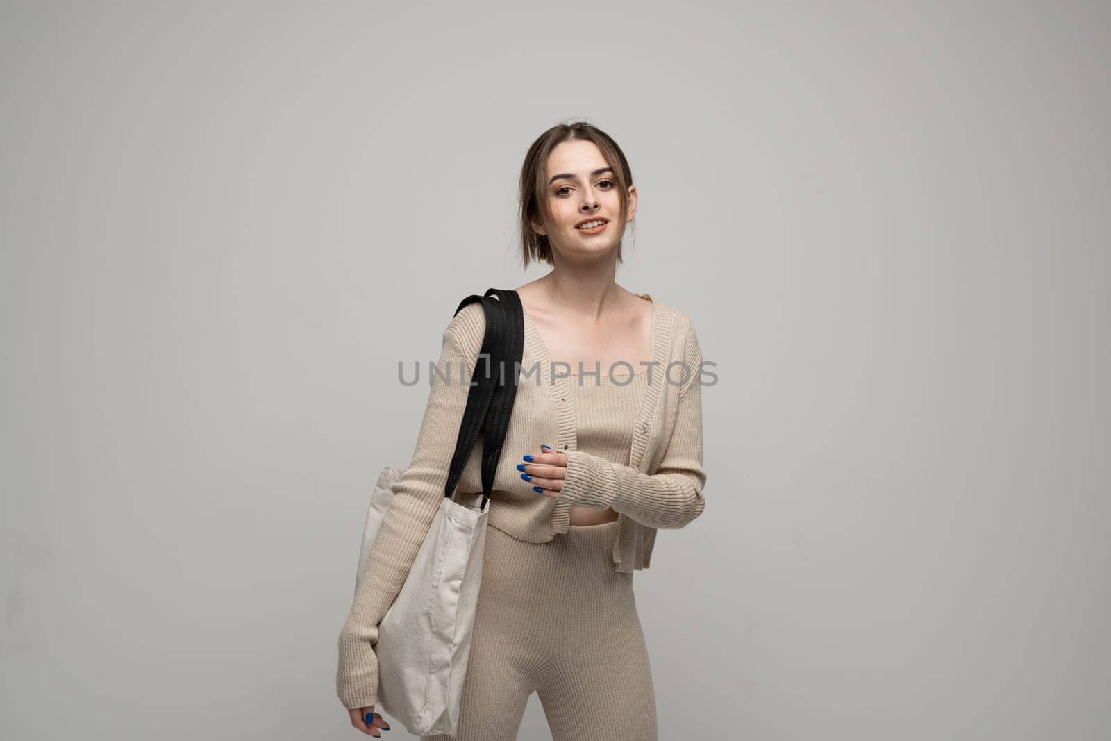 Happy, smiling brunette young woman carrying reusable cotton bag. Concept of recycle for better environment. No plastic