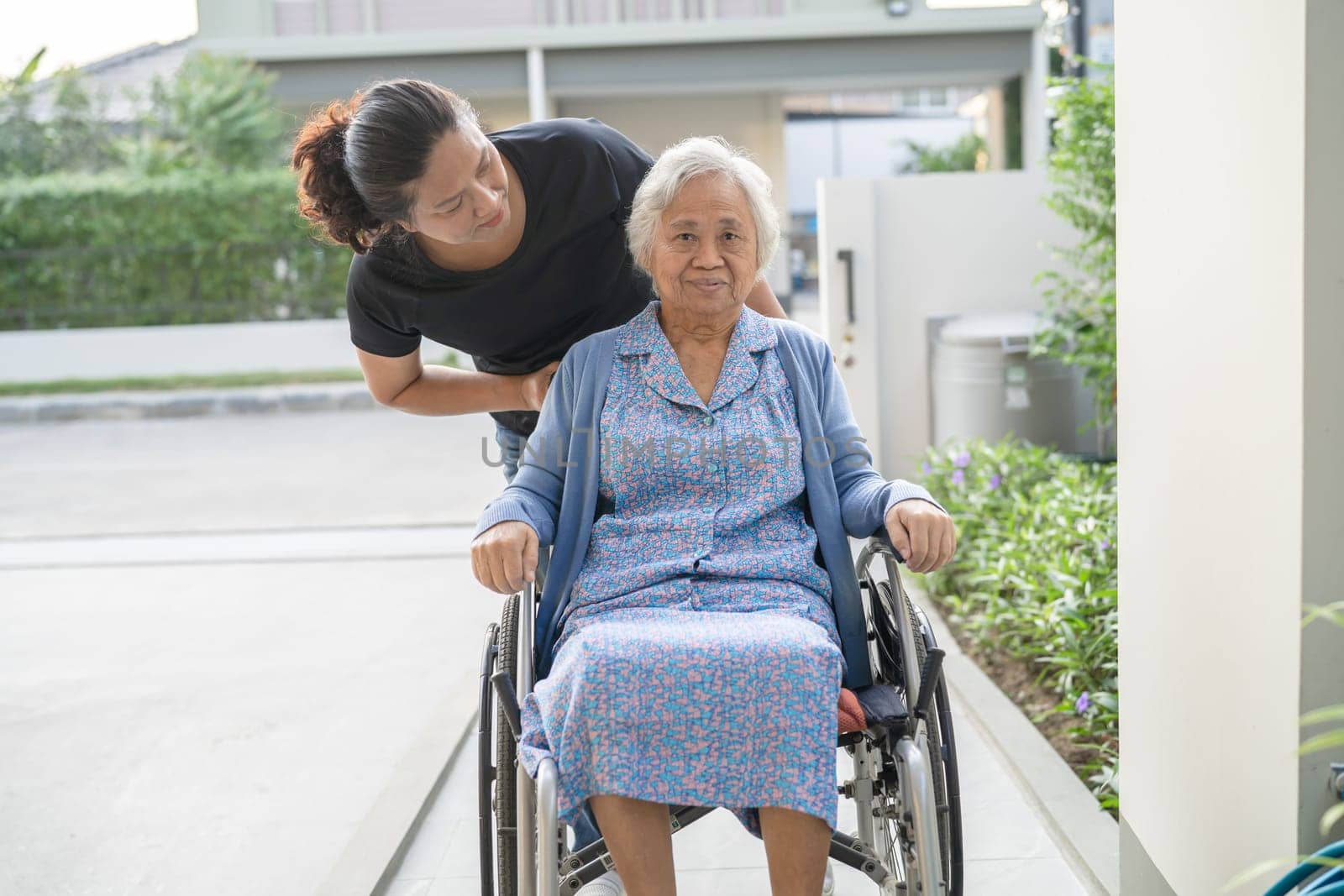 Caregiver help and care Asian elderly woman patient sitting on wheelchair to ramp in nursing hospital, healthy strong medical concept. by pamai