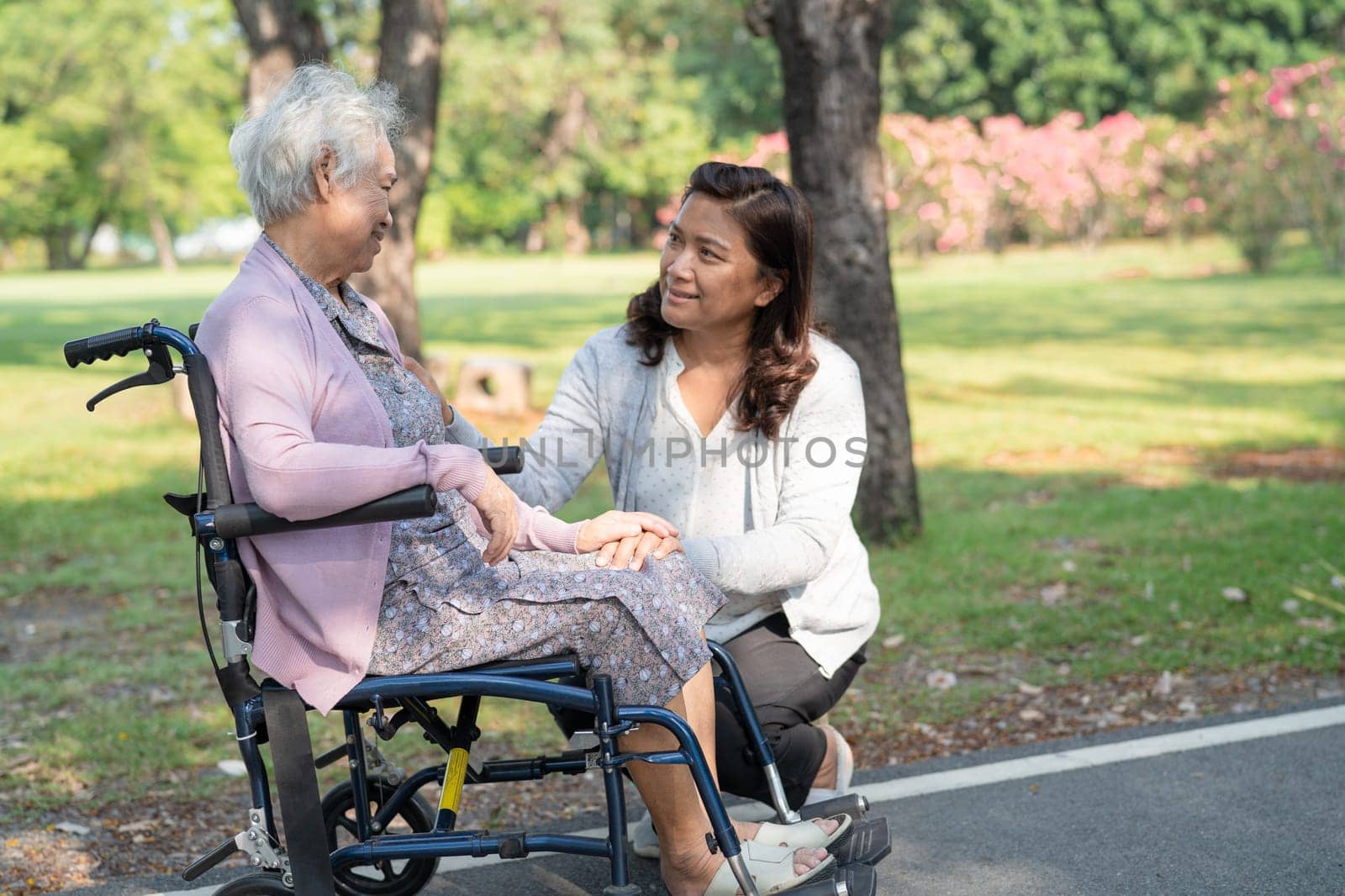 Caregiver help and care Asian elderly woman use walker with strong health while walking at park in happy fresh holiday. by pamai