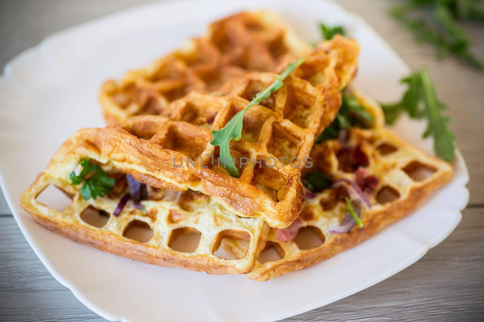 Egg omelette stuffed with onions and herbs, fried in the form of waffles, on a wooden table