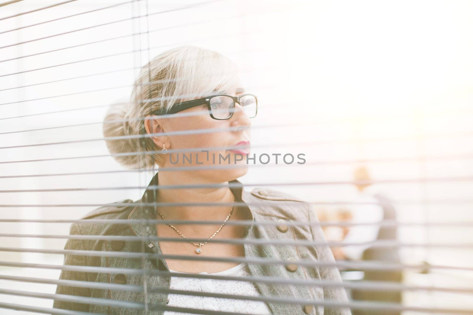 close up. serious business woman looking through office window by SmartPhotoLab