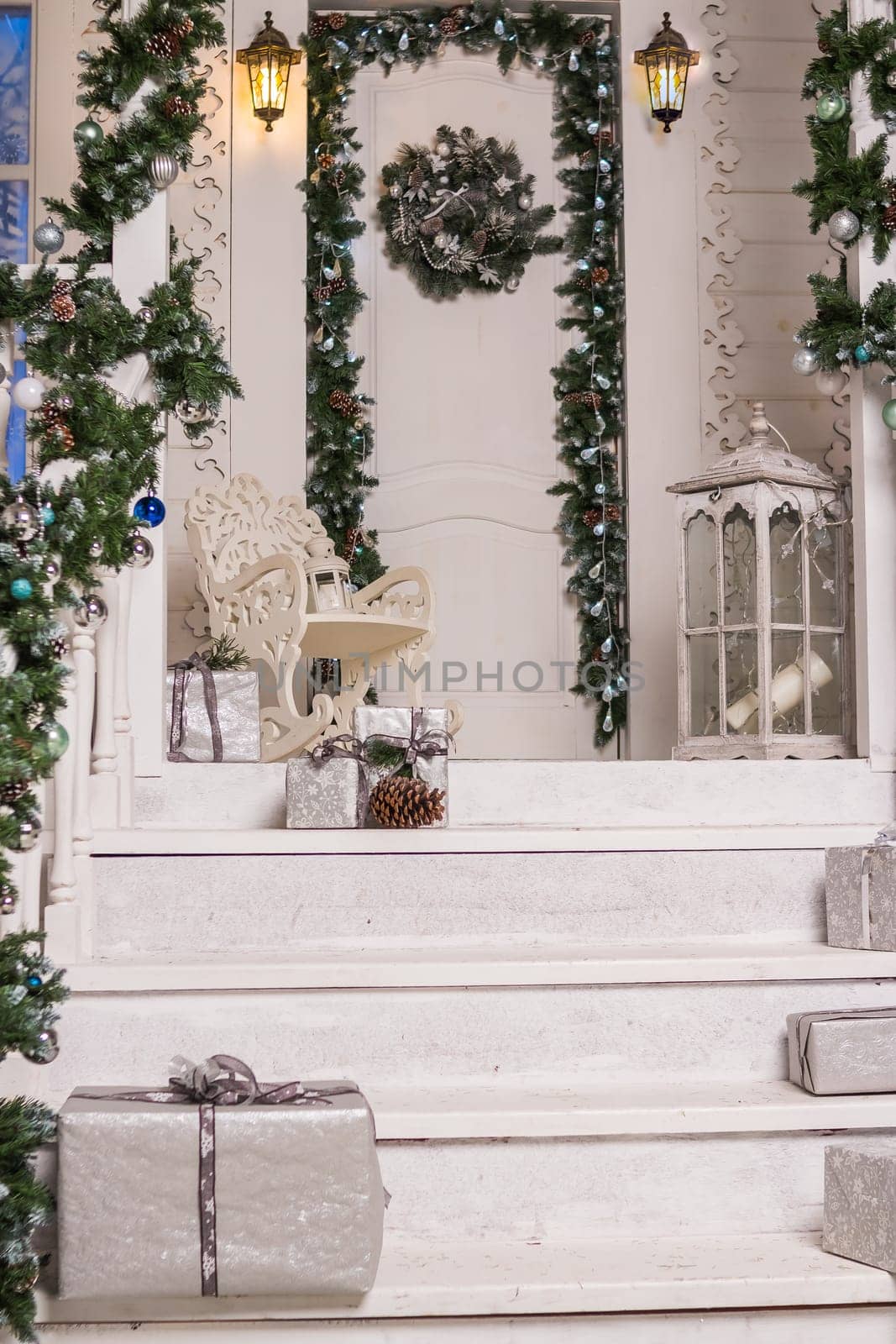 house entrance decorated for holidays. Christmas decoration. garland of fir tree branches and lights on the railing