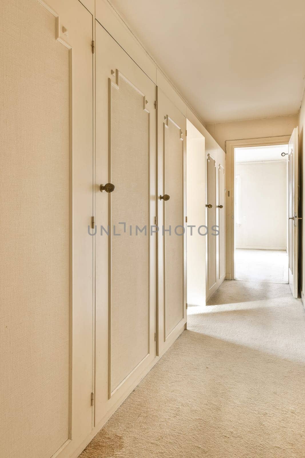 an empty room with white walls and beige carpeting, there is no one person in the room to be seen