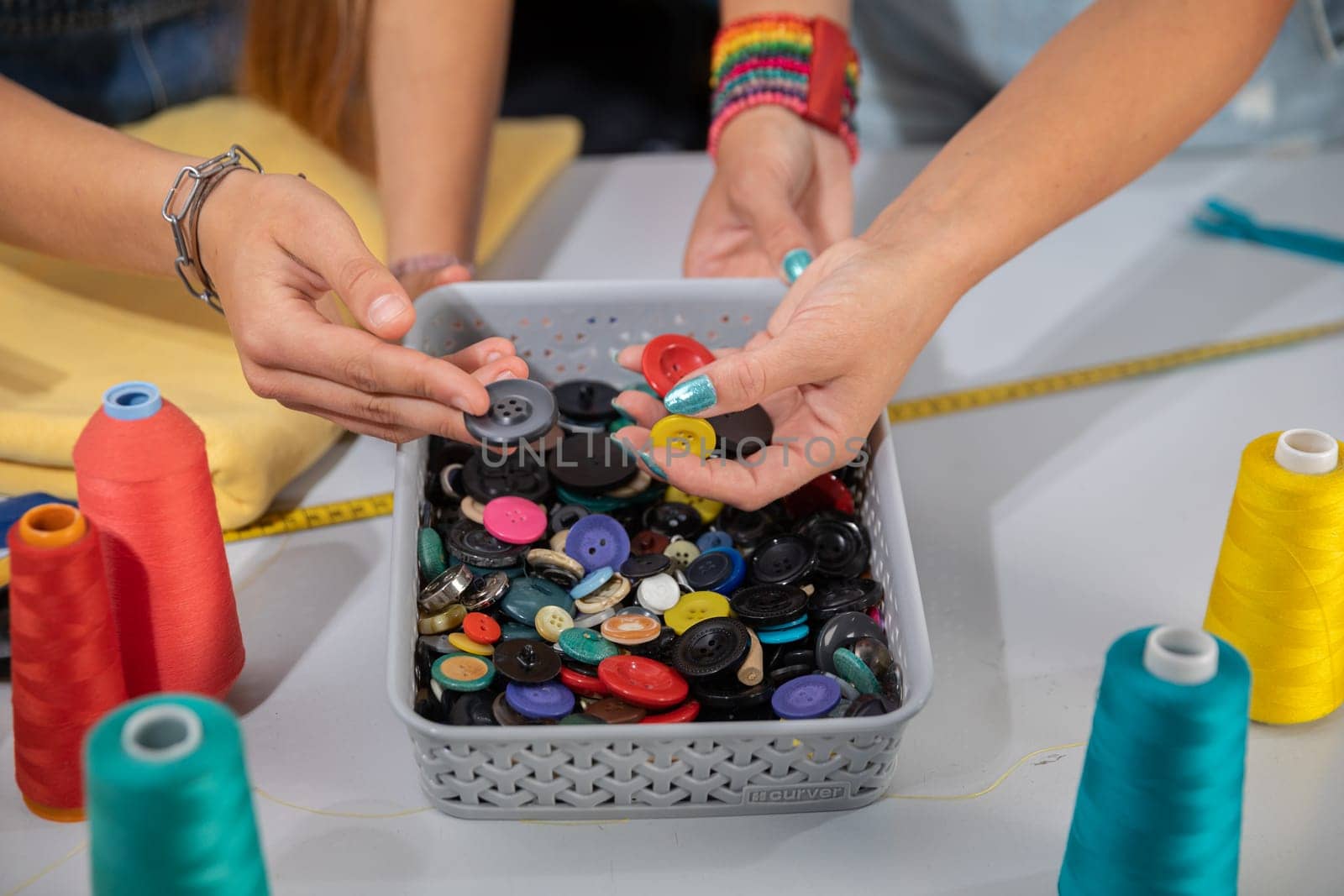 Clothing designers work together to carefully select the right color of buttons that will be used for the new spring collection. Work in the sewing studio.