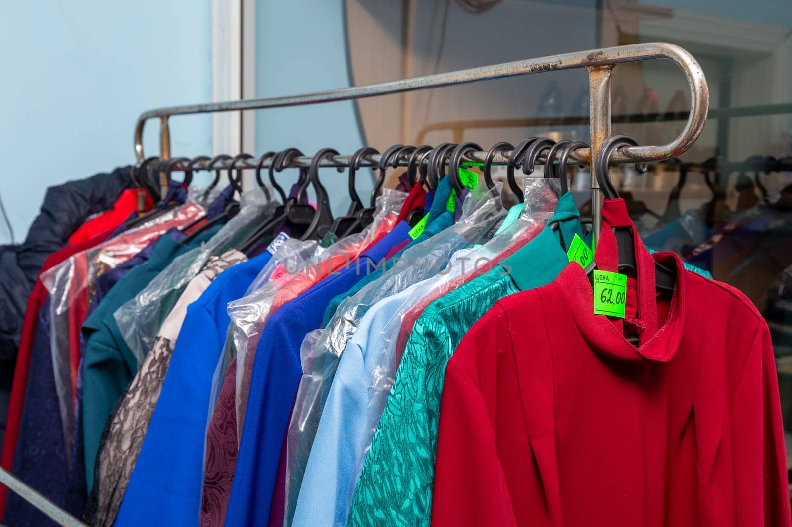 Hangers with men suits and women clothes for the deceased in a funeral goods store. by BY-_-BY