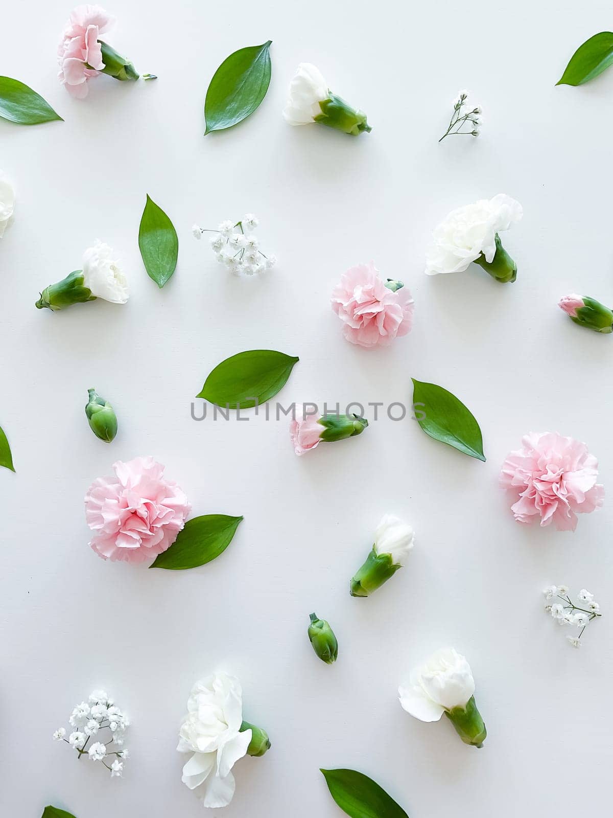 Floral pattern of pink and white carnations, green leaves, buds and gypsophila on a white background. Flat lay, top view. Valentine's background. Floral pattern. Flowers pattern. Floral pattern texture