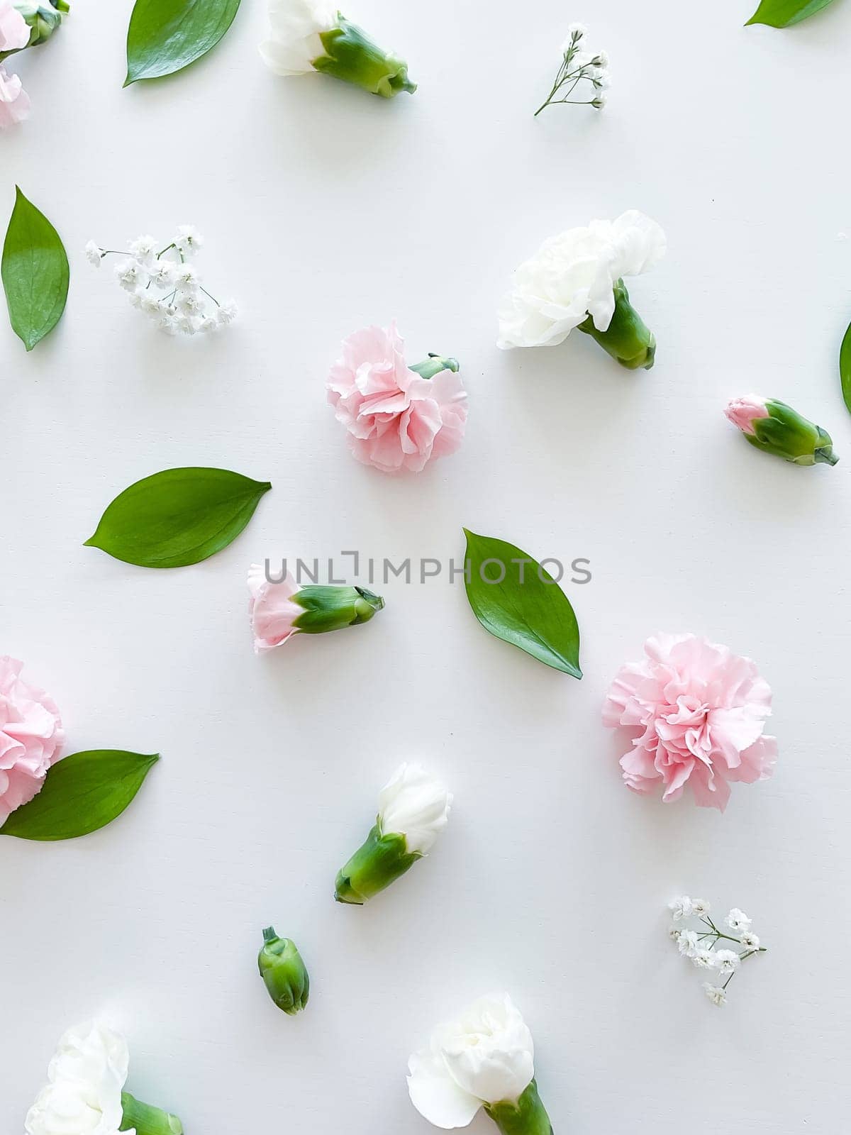 Floral pattern of pink and white carnations, green leaves, buds and gypsophila on a white background. Flat lay, top view. Valentine's background. Floral pattern. Flowers pattern. Floral pattern texture