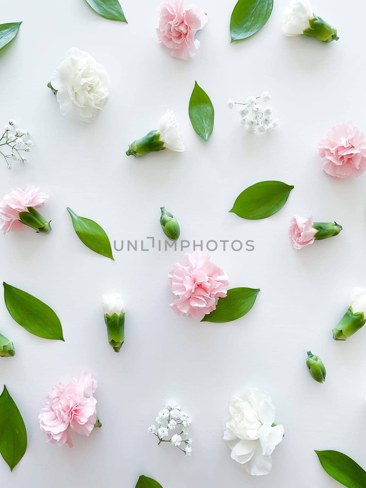 Floral pattern of pink and white carnations, green leaves, buds and gypsophila on a white background. Flat lay, top view. Valentine's background. Floral pattern. Flowers pattern. Floral pattern texture