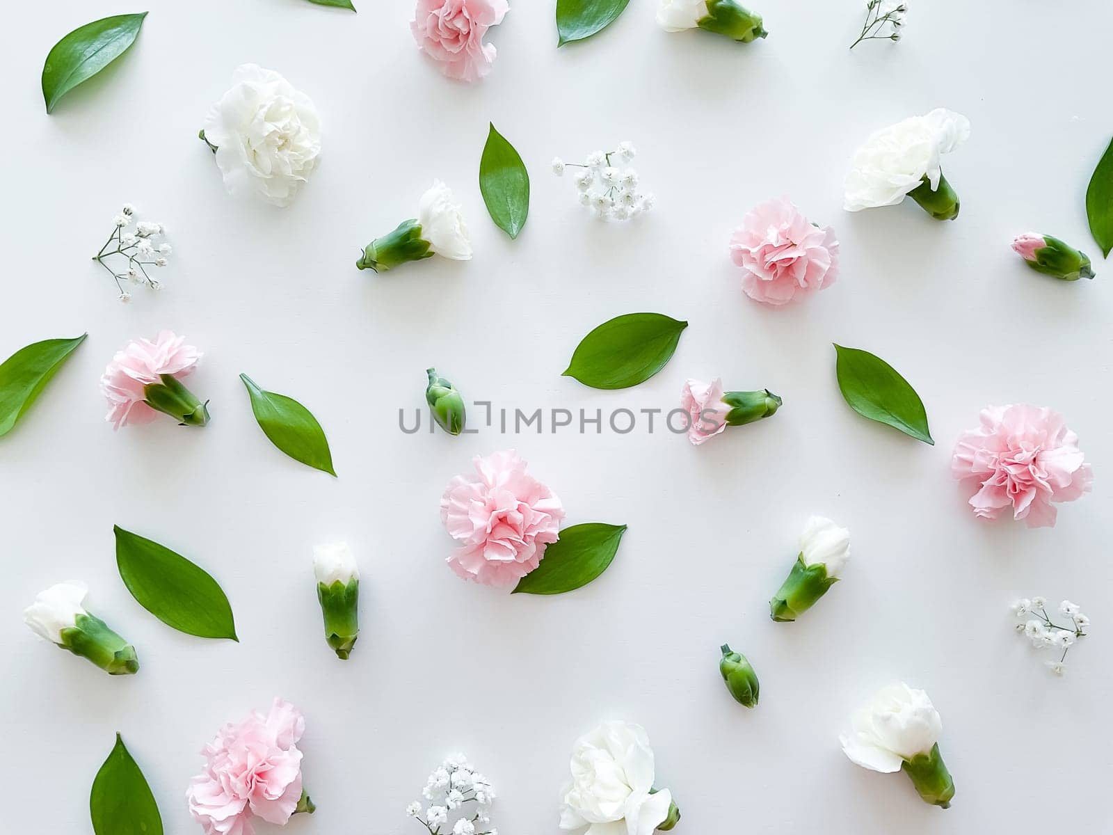 Floral pattern of pink and white carnations, green leaves, buds and gypsophila on a white background. Flat lay, top view. Valentine's background. Floral pattern. Flowers pattern. Floral pattern texture