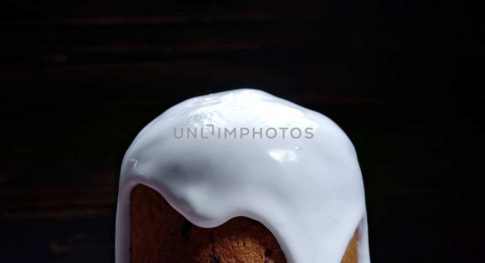 Easter cake, decoration with white glaze and colorful sugar sprinkling, traditional bakery. Spring christian religious holiday. Delicious homemade festive sweets. Black background.