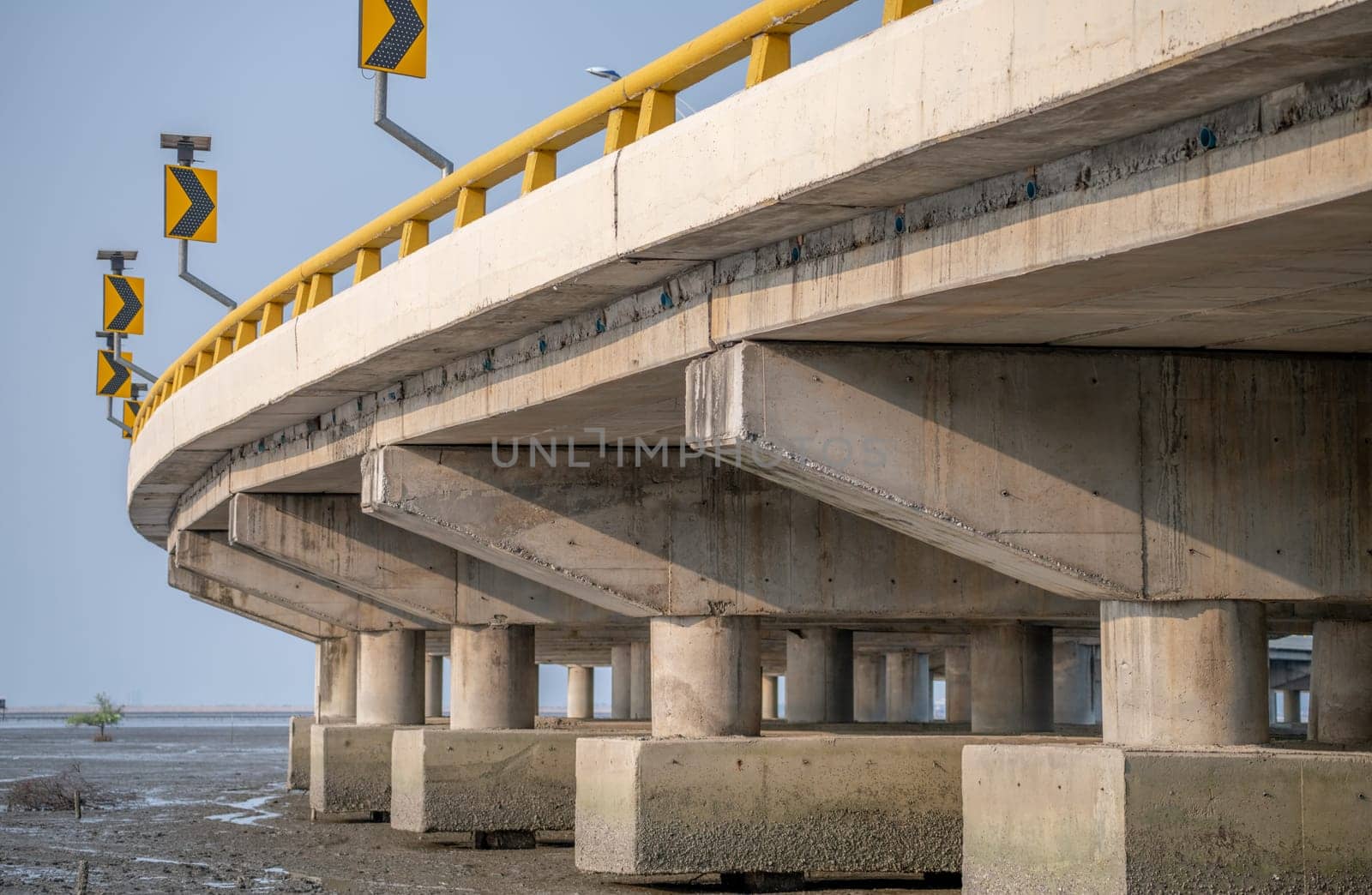 Structure of reinforced concrete bridge along the sea. Bottom view of concrete bridge. Concrete bridge engineering construction. Modern cement bridge with strong column architecture. Infrastructure.