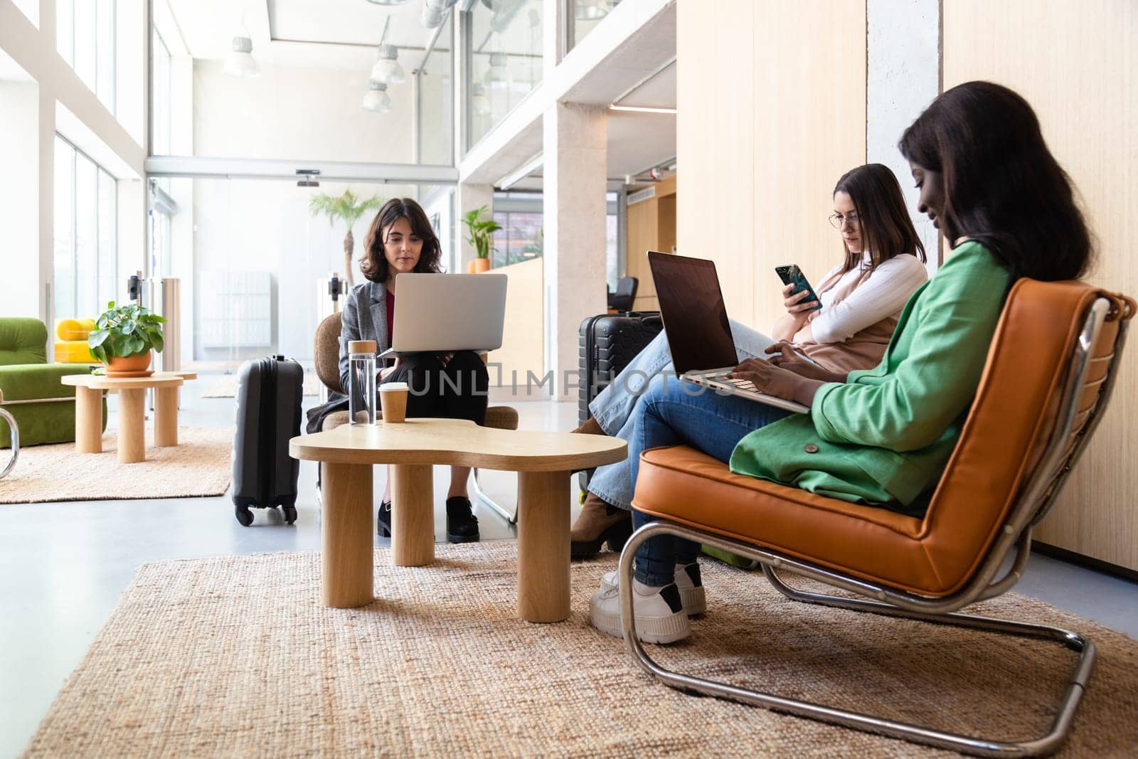 Multiracial women work using laptop in hotel lobby reception. Travel and lifestyle concepts.