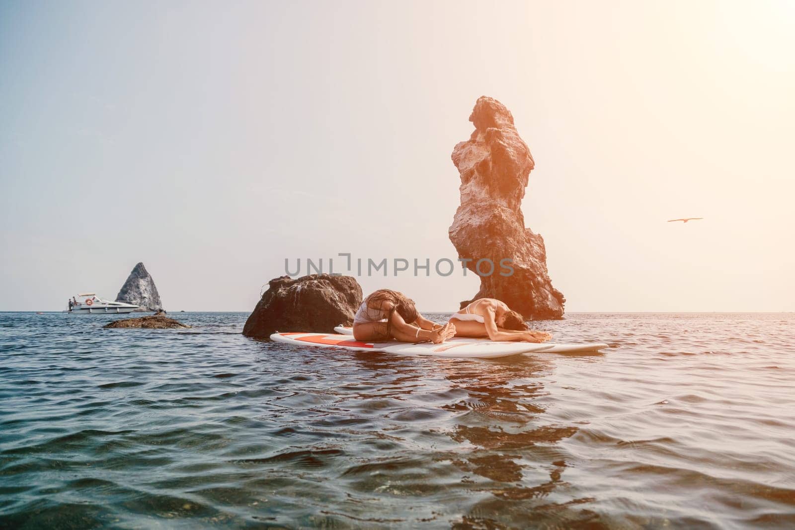 Woman sup yoga. Middle age sporty woman practising yoga pilates on paddle sup surfboard. Female stretching doing workout on sea water. Modern individual hipster outdoor summer sport activity