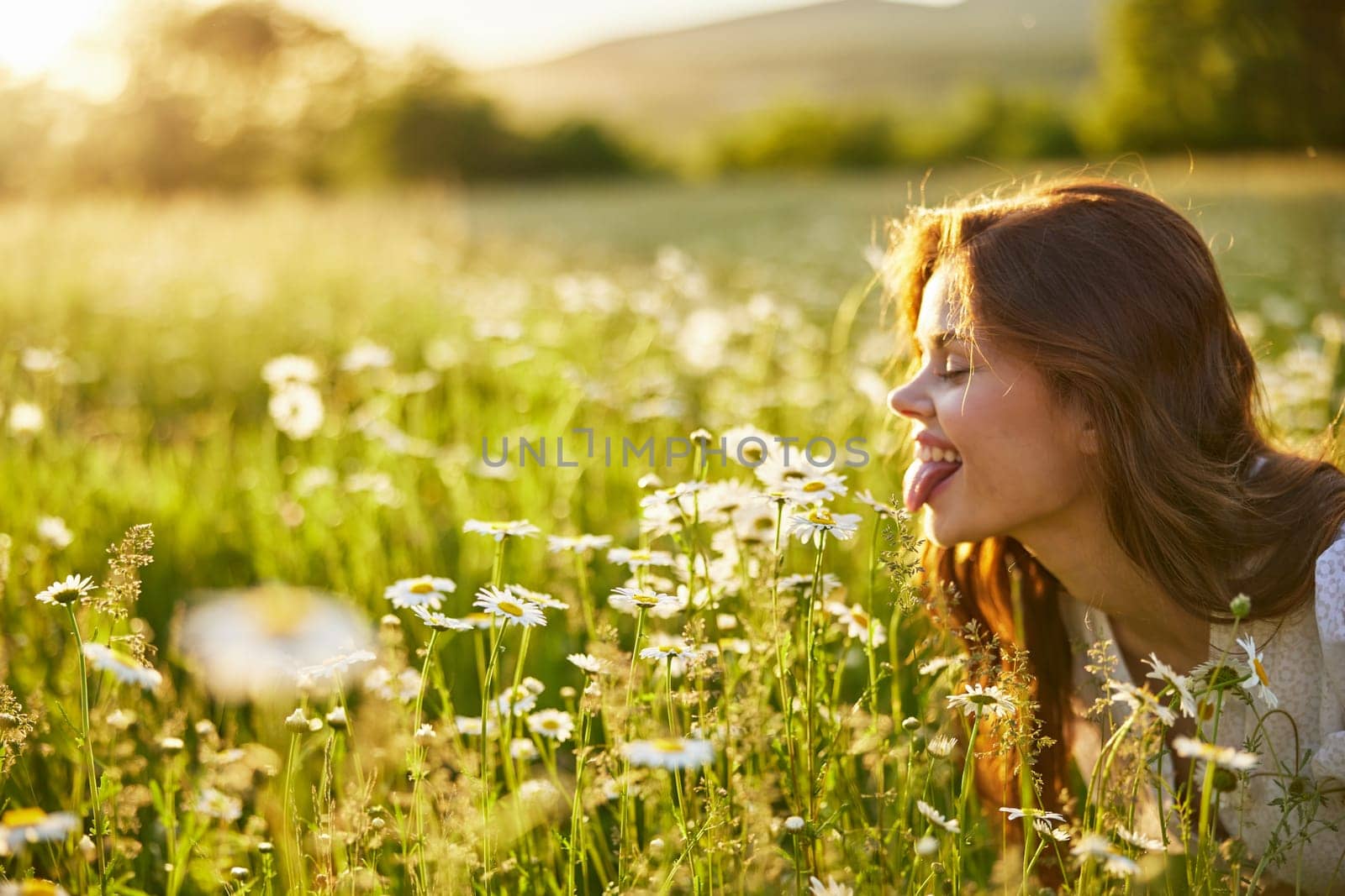 portrait of a beautiful, happy woman in a chamomile field, showing her tongue and enjoying nature. High quality photo
