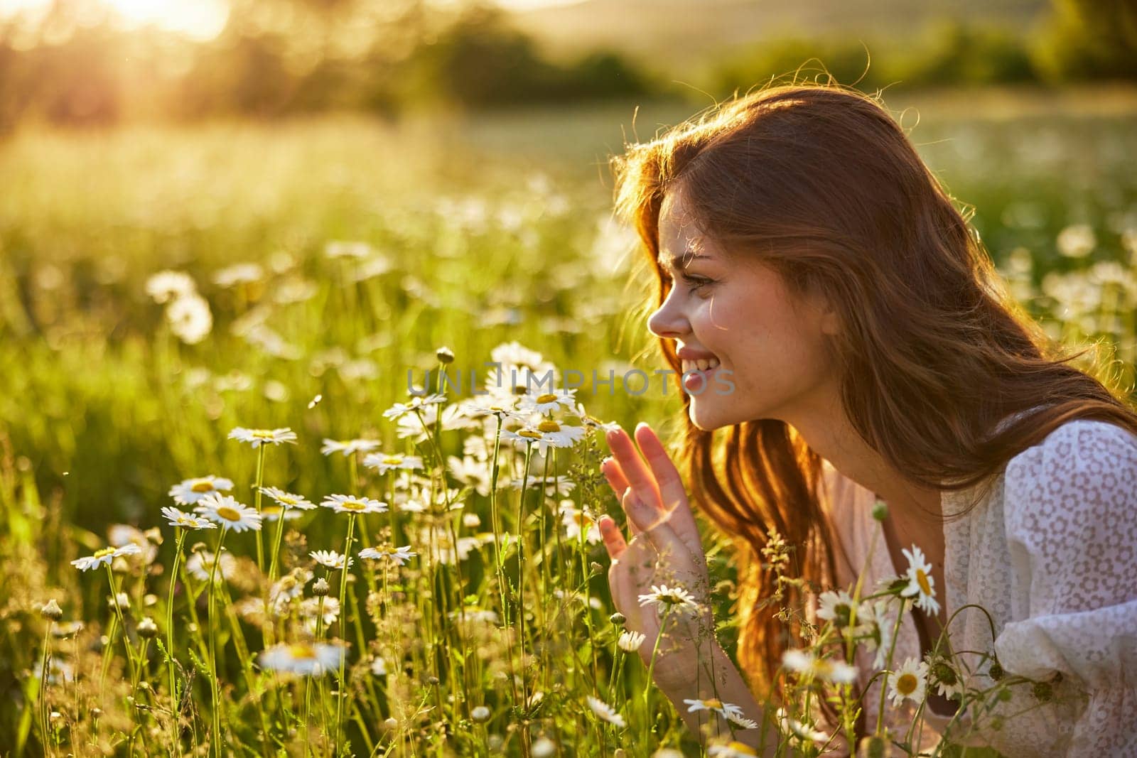 portrait of a beautiful, happy woman in a chamomile field, smelling flowers and enjoying nature by Vichizh