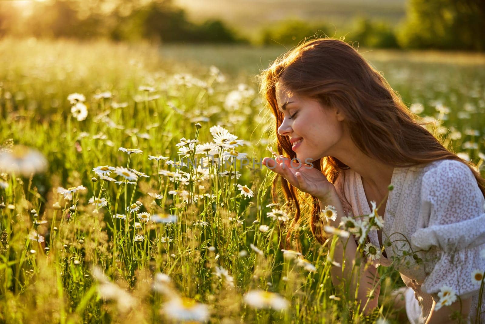 portrait of a beautiful, happy woman in a chamomile field, smelling flowers and enjoying nature by Vichizh