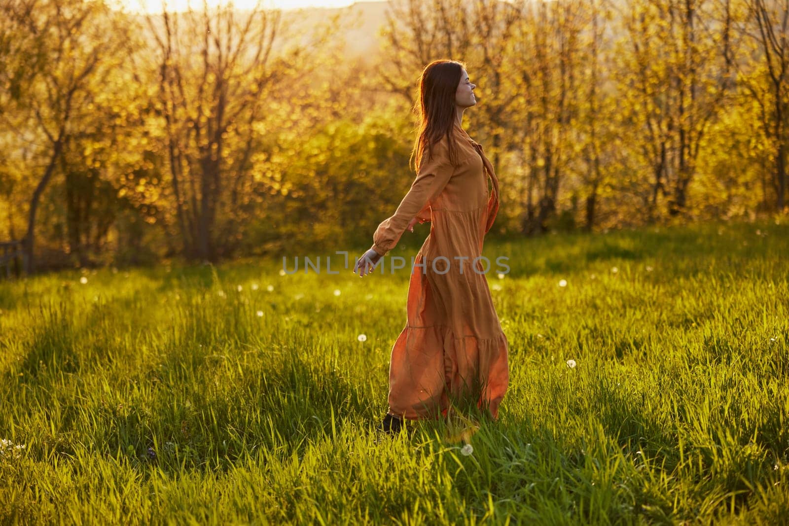 a joyful woman runs through a green field during the sunset enjoying a warm summer day and nature. Horizontal photography in nature. High quality photo