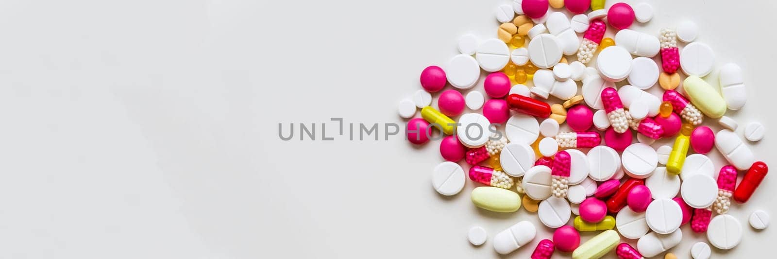 Pile of colorful medicine pills, white, blue, yellow and red, sitting on white background