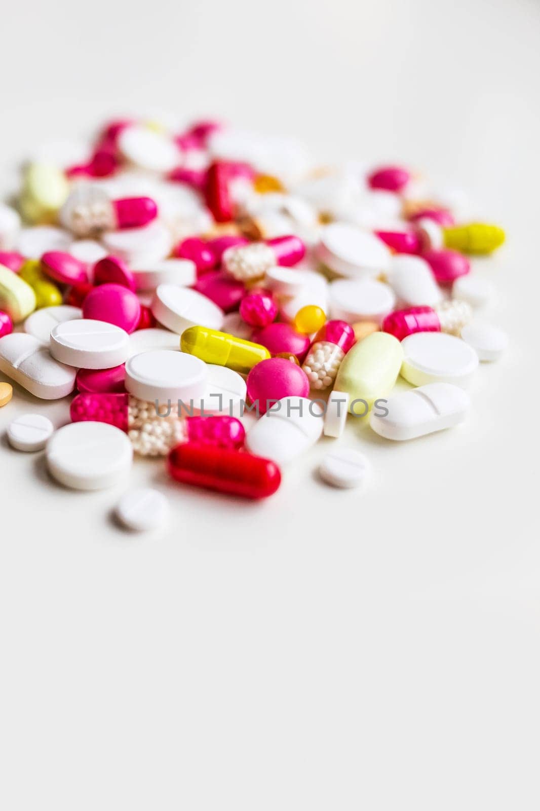 Pile of colorful medicine pills, white, blue, yellow and red, sitting on white background