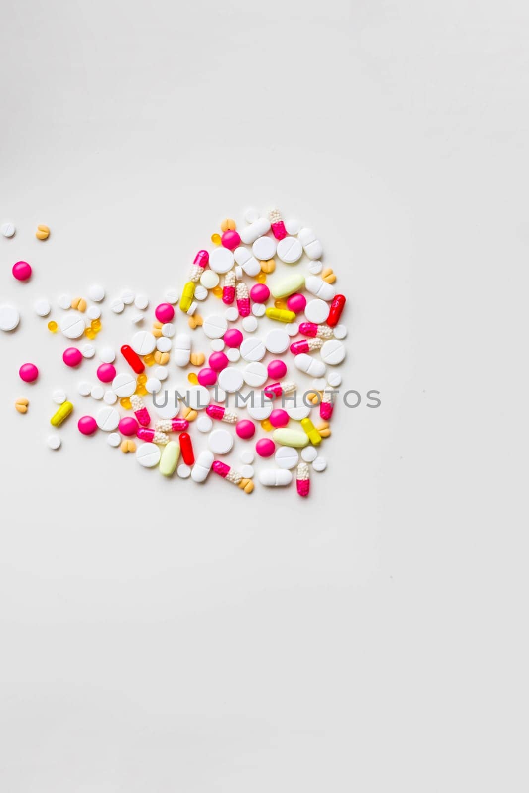 Pile of colorful medicine pills, white, blue, yellow and red, sitting on white background