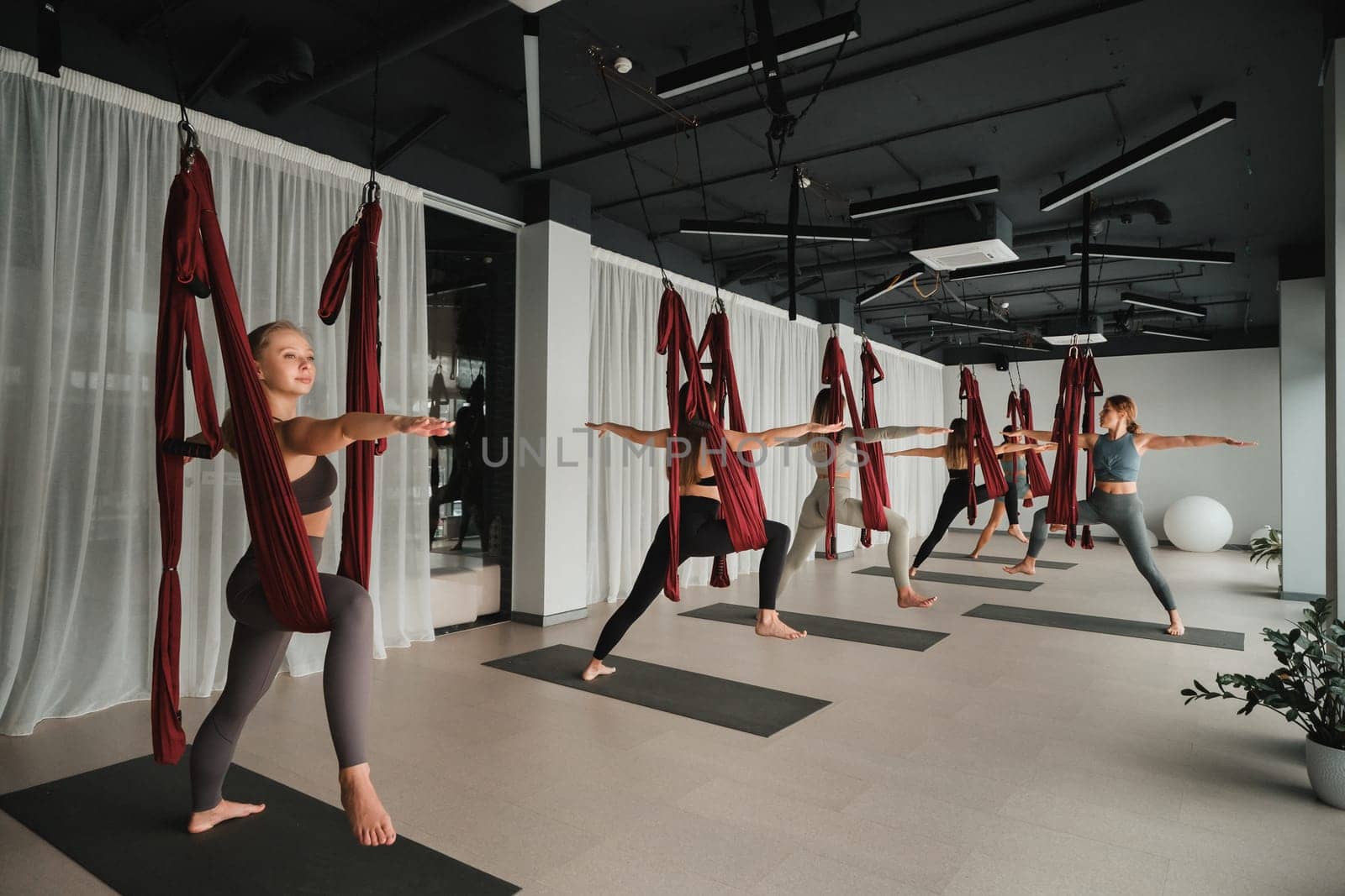 A group of women play sports on hanging hammocks. Fly yoga in the gym.
