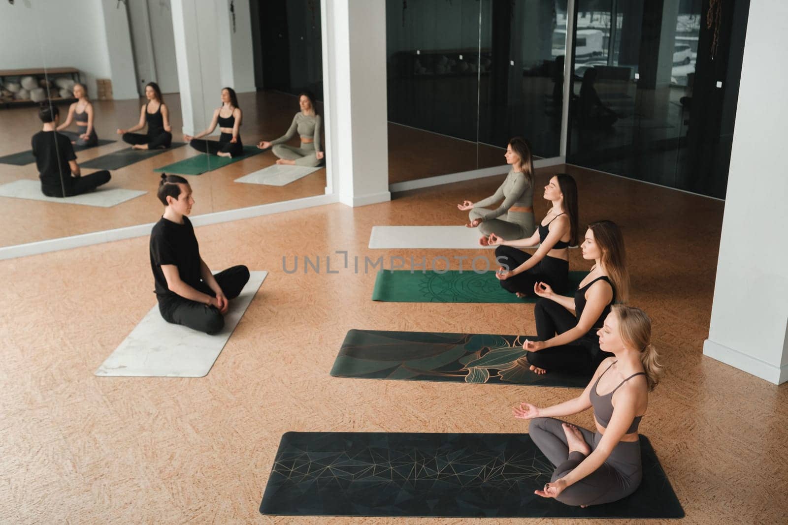 a group of girls do yoga in the gym under the guidance of a coach by Lobachad