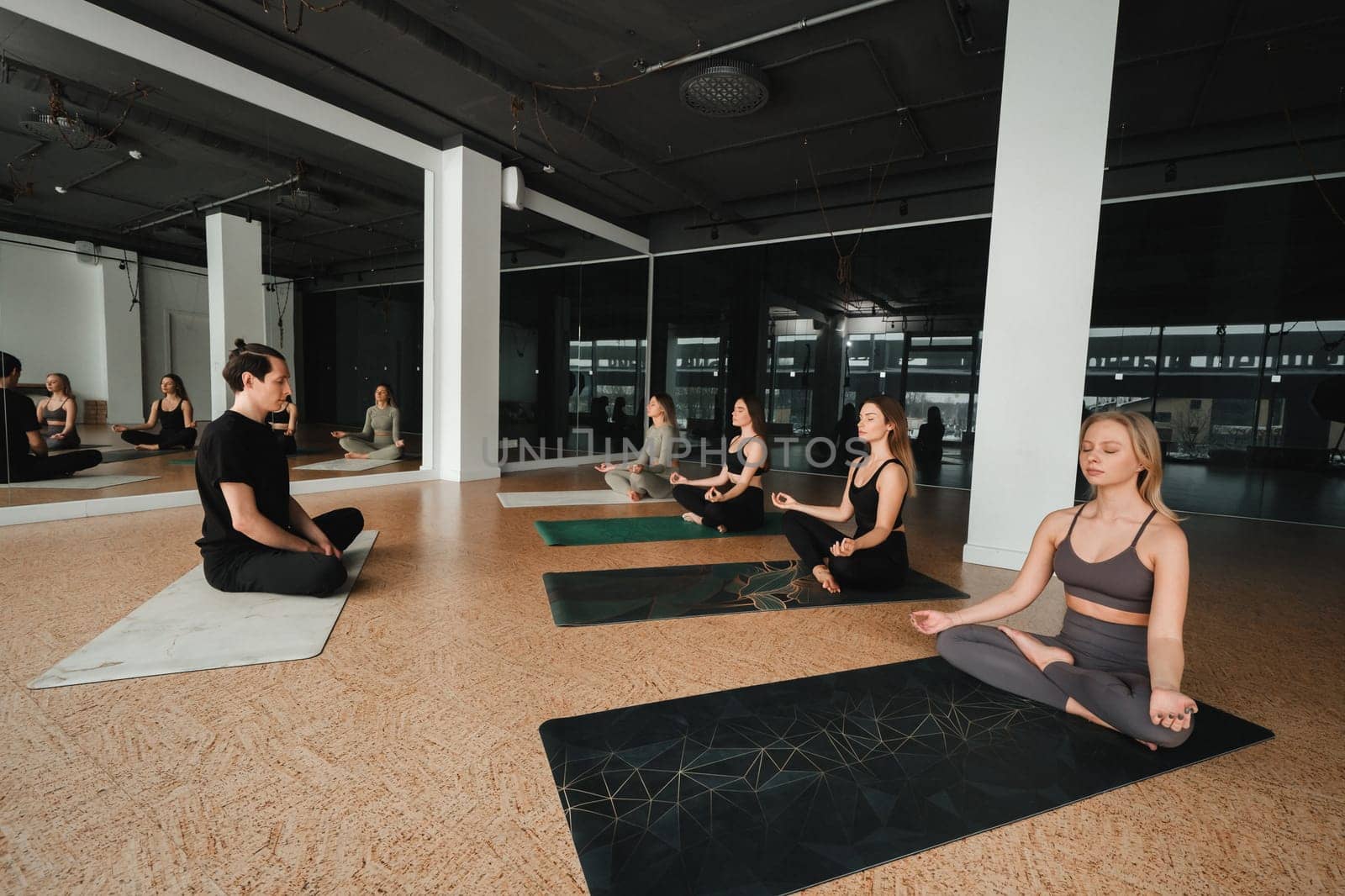 a group of girls do yoga in the gym under the guidance of a coach.