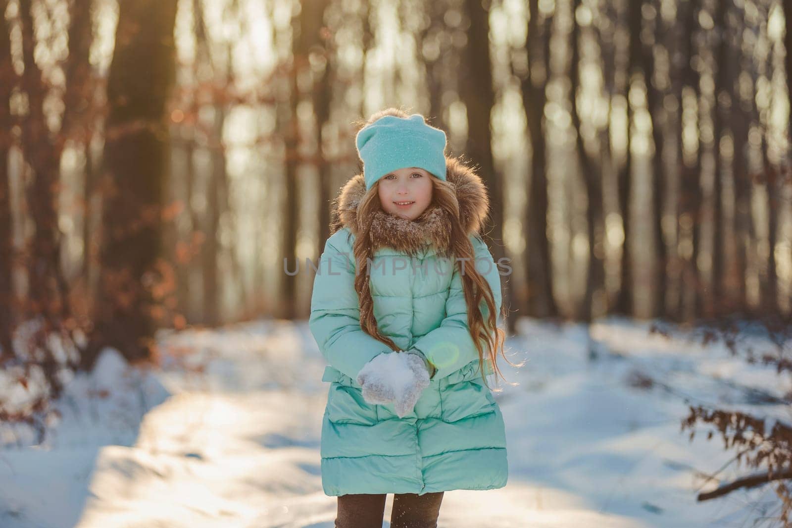 portrait of a girl against the backdrop of a winter forest illuminated by the sun