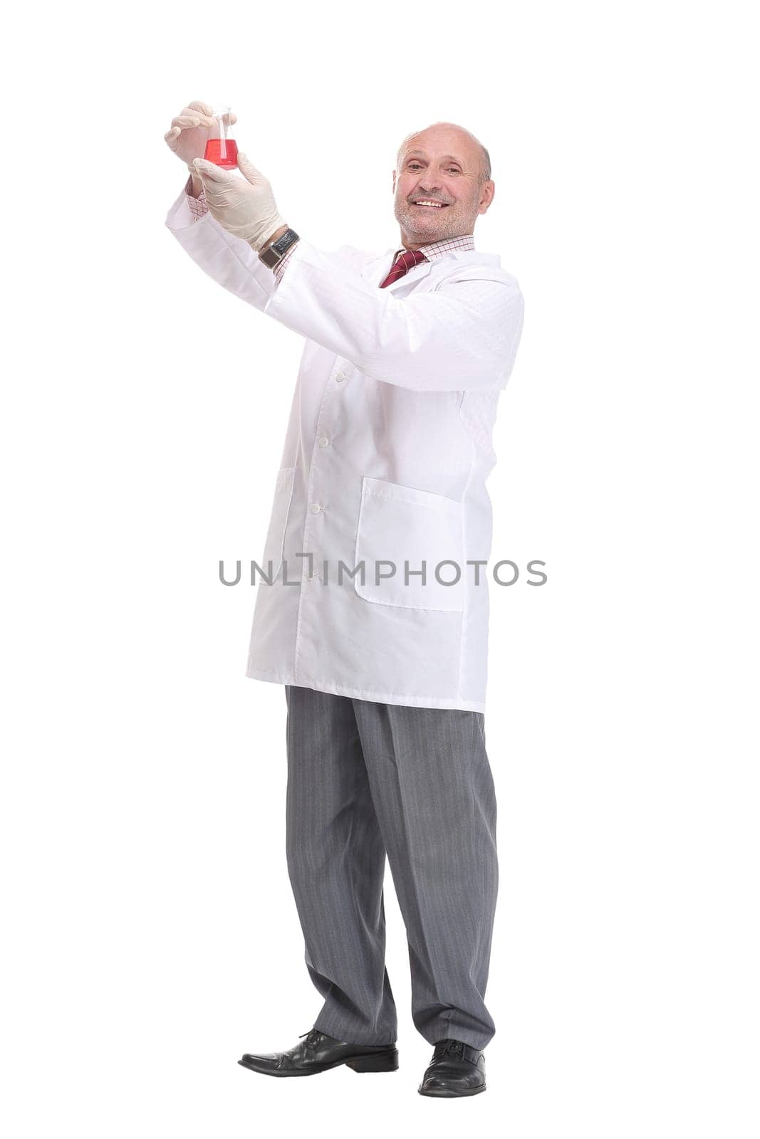 Mature scientist with grey hair and beard in white coat standing with beaker in his hand and holding medical test isolated on white background