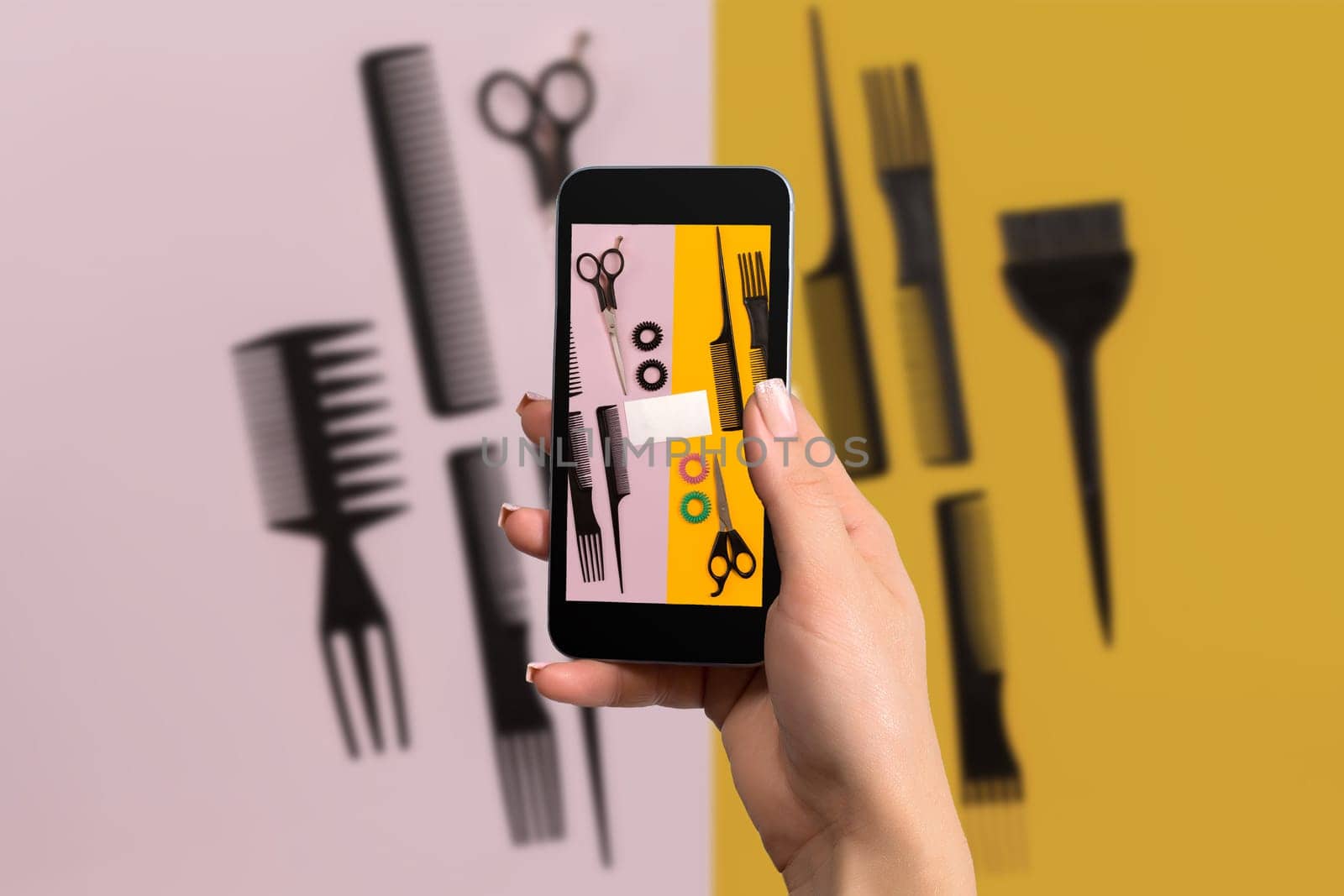 Female hand with a smartphone makes a photo set of combs on pink and yellow background. Still life. Flat lay
