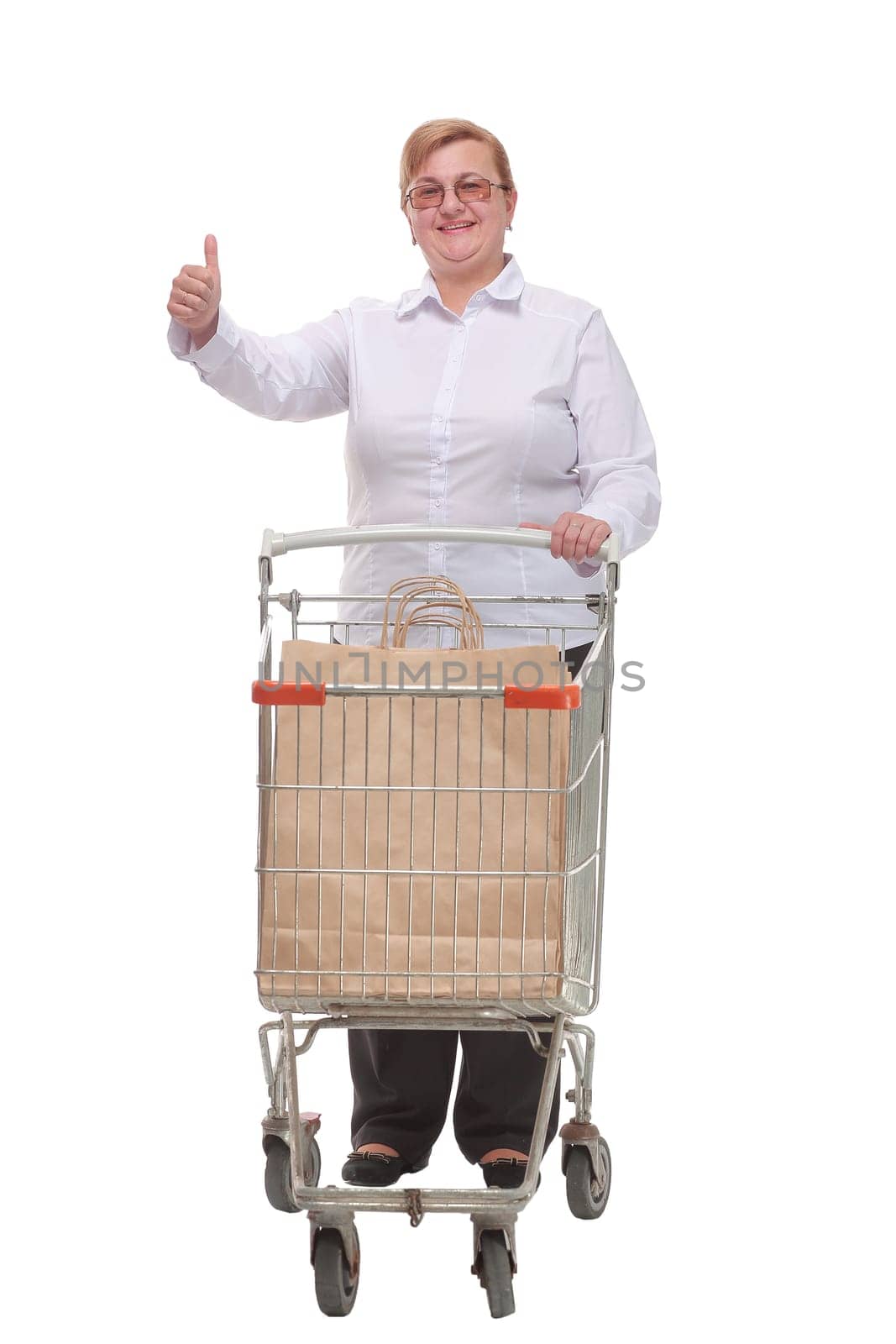 Smiling woman with shopping cart and bags in it showing thumbs up. Happiness, shopping and people concept