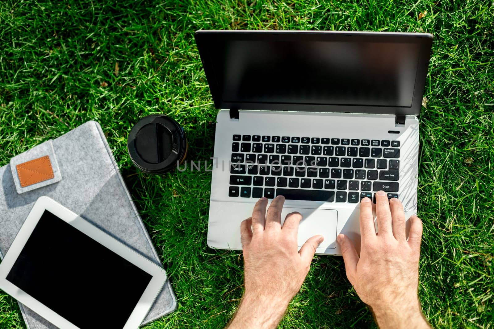 Close-up shot of handsome man's hands touching laptop computer's screen. Businessman using a laptop computer and sitting on the ground.