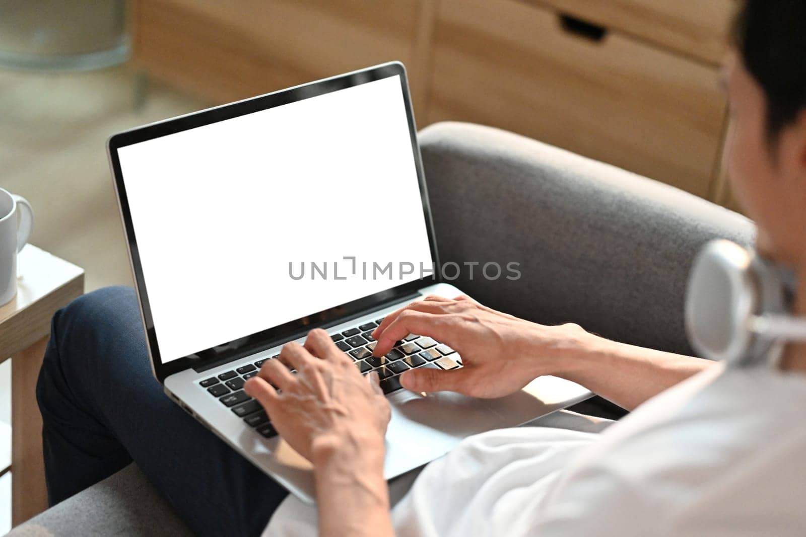 Man relaxing on couch working remotely, surfing internet on laptop. Blank screen for your advertising text message.