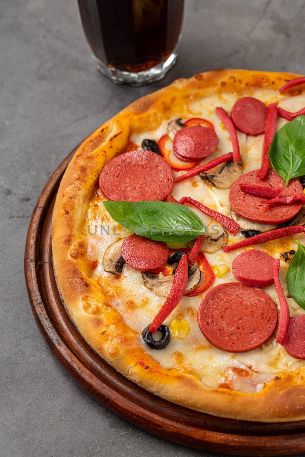 Mixed pizza with sausage, salami and mushrooms on a stone table