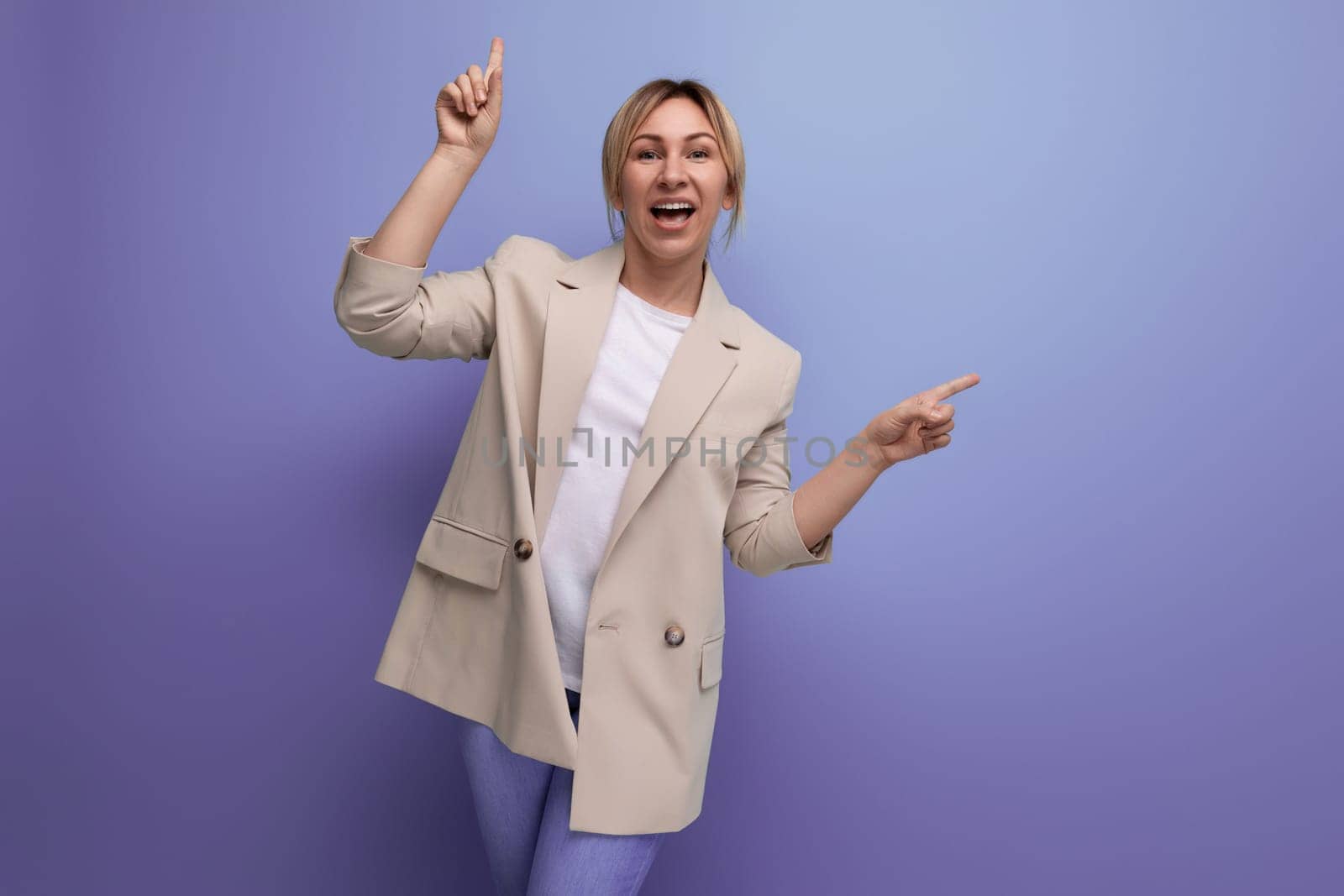 charming blonde young adult in jacket smiling on studio background.