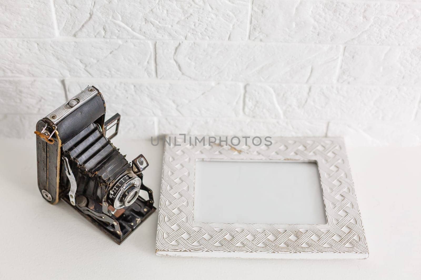 Decorative vases with flower and old camera on white shelf on blue wallpaper background