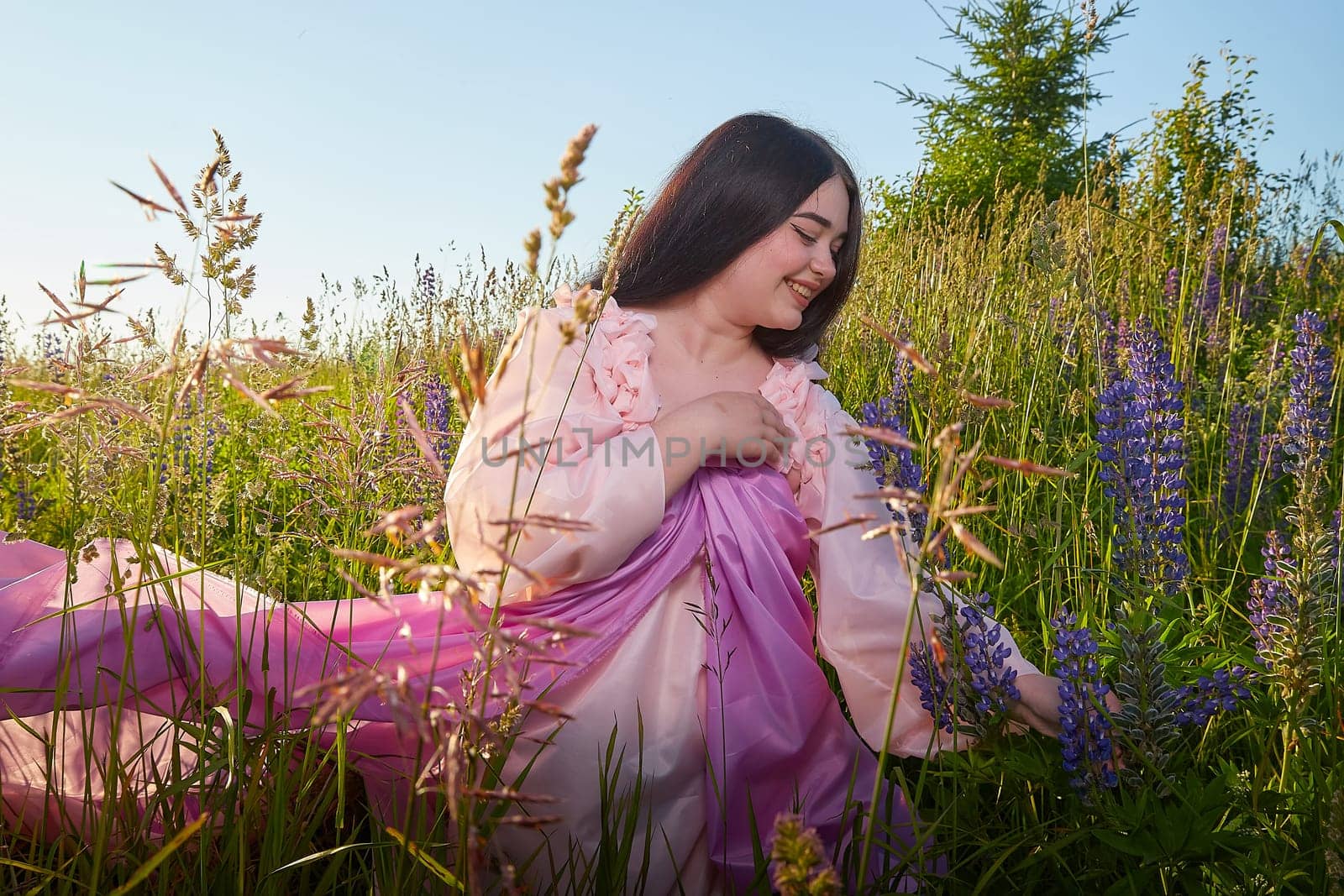 Young plump curvy beautiful teenage girl in a field or meadow on sunny summer day in the evening sunset sun. Plump black-haired and black-eyed oriental model from the east fairy tale