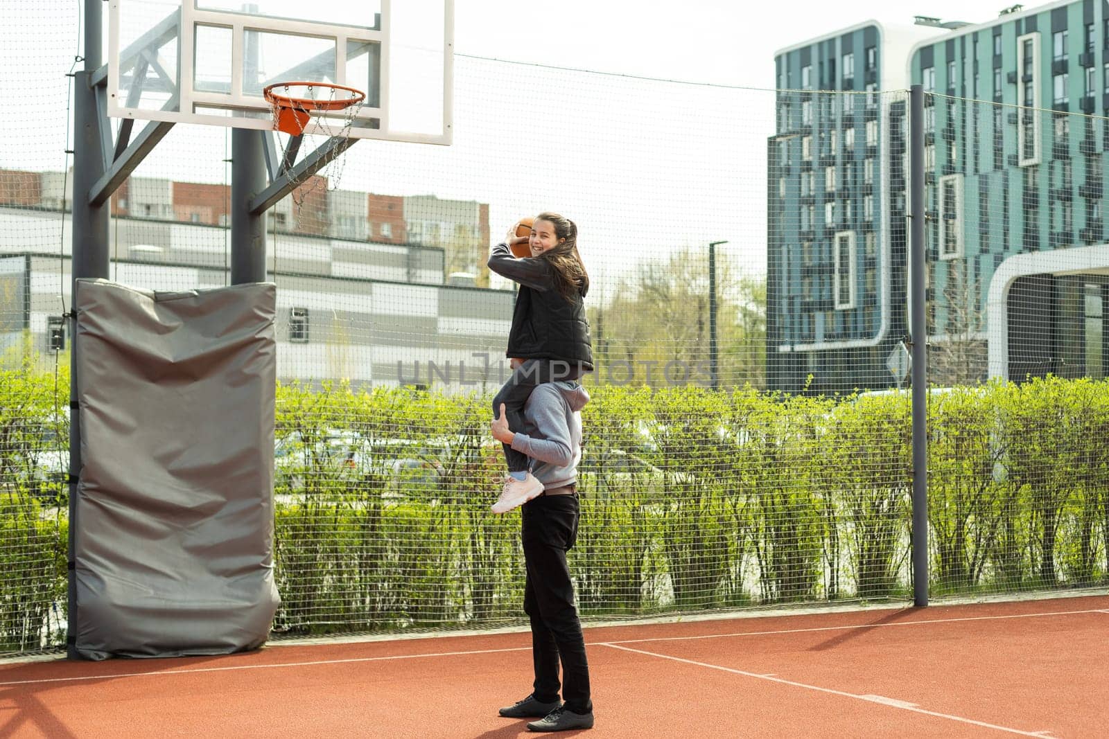 Happy father and teen daughter outside at basketball court