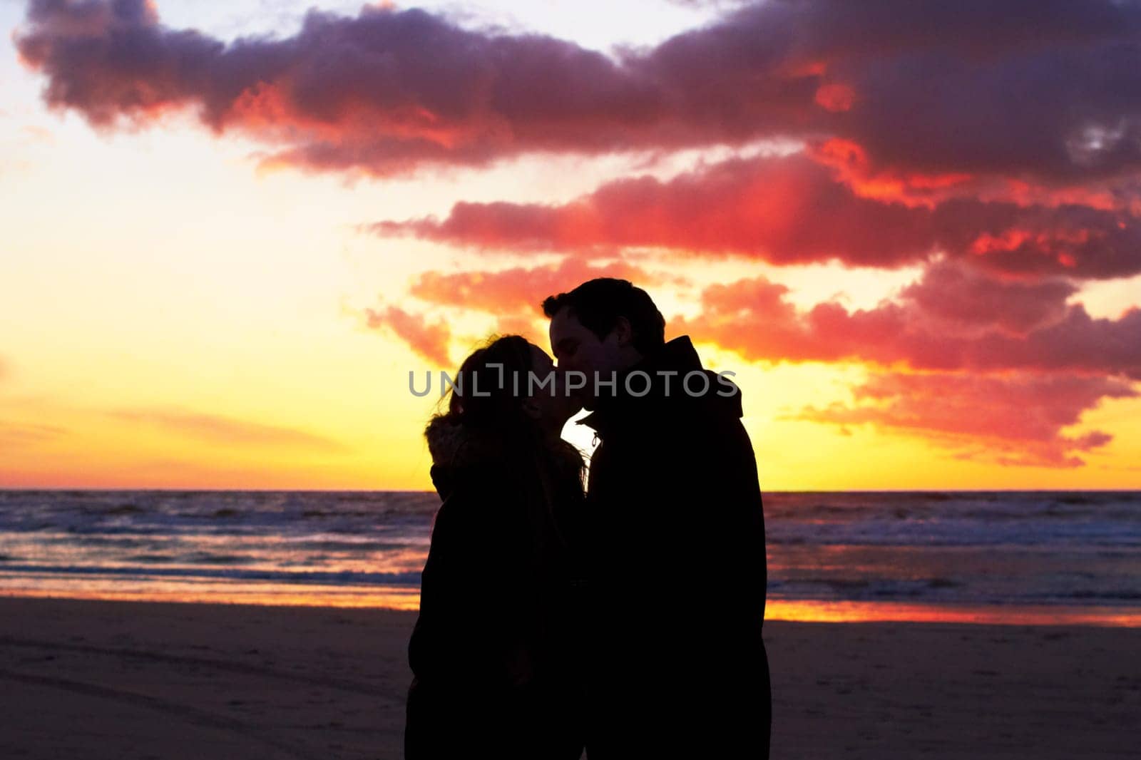 Beach, sunset and couple silhouette kiss in nature with love, freedom and romance outdoors. Shadow, romantic and people kissing at sunrise, sweet and together for travel, vacation or holiday in Bali by YuriArcurs
