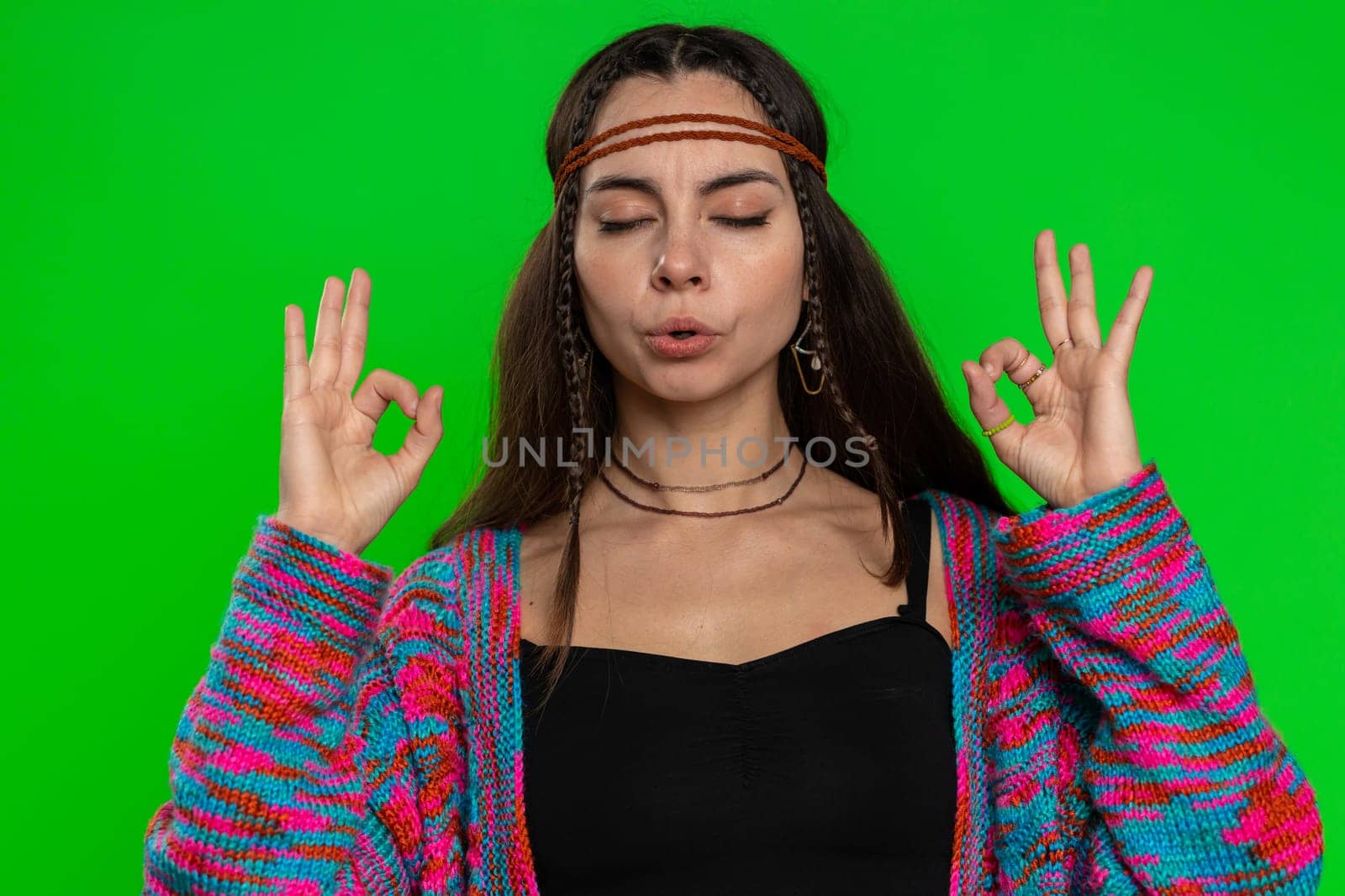 Keep calm down, relax, inner balance. Young woman breathes deeply with mudra gesture, eyes closed, meditating with concentrated thoughts, peaceful mind. Girl isolated on green chroma key background