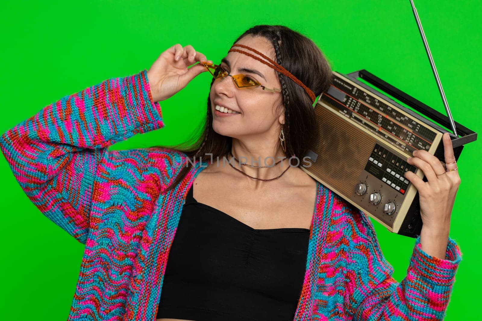 Woman in sunglasses using retro tape record player to listen music, disco dancing of favorite track, having fun, entertaining, fan of vintage technologies. Girl isolated on green chroma key background
