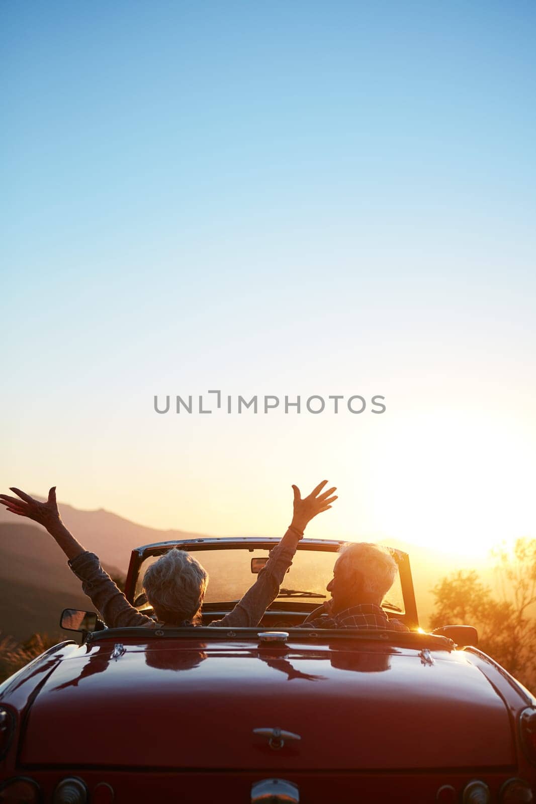 No regrets. a joyful senior couple enjoying the sunset during a roadtrip. by YuriArcurs