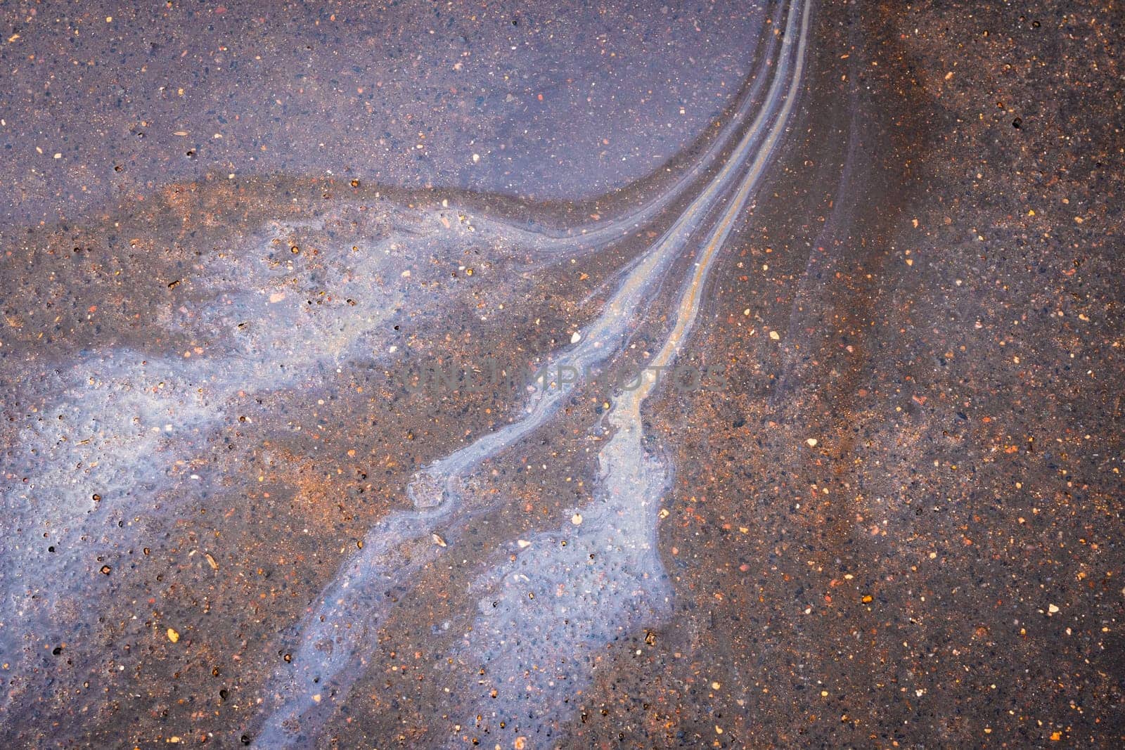 Rainbow gasoline oil spill on the pavement as a texture or background.