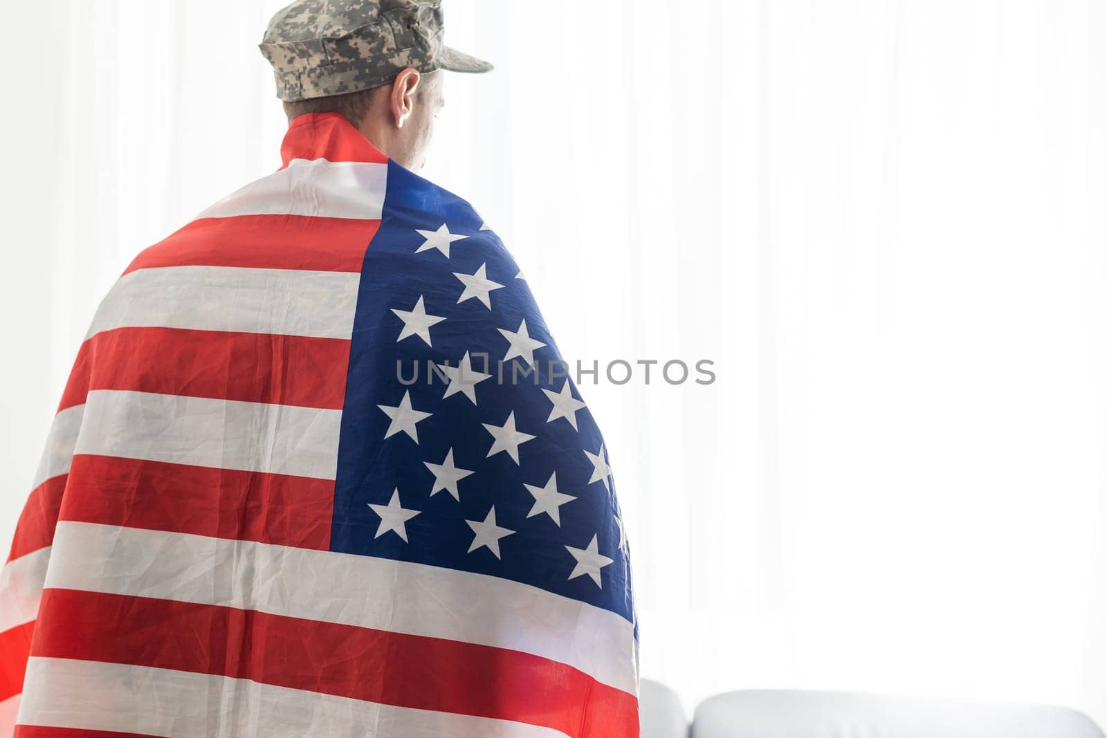 soldier in uniform and cap holding american flag.