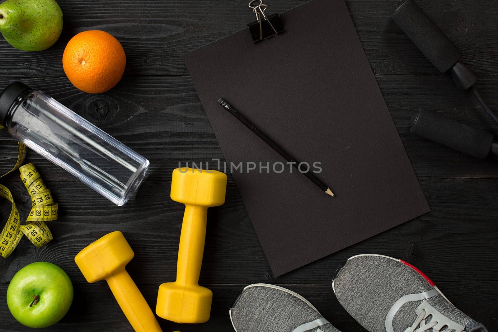 Athlete's set with female clothing, sneakers and bottle of water on dark background. Top view. Copy space. Still life. Ideal for sporty blog.