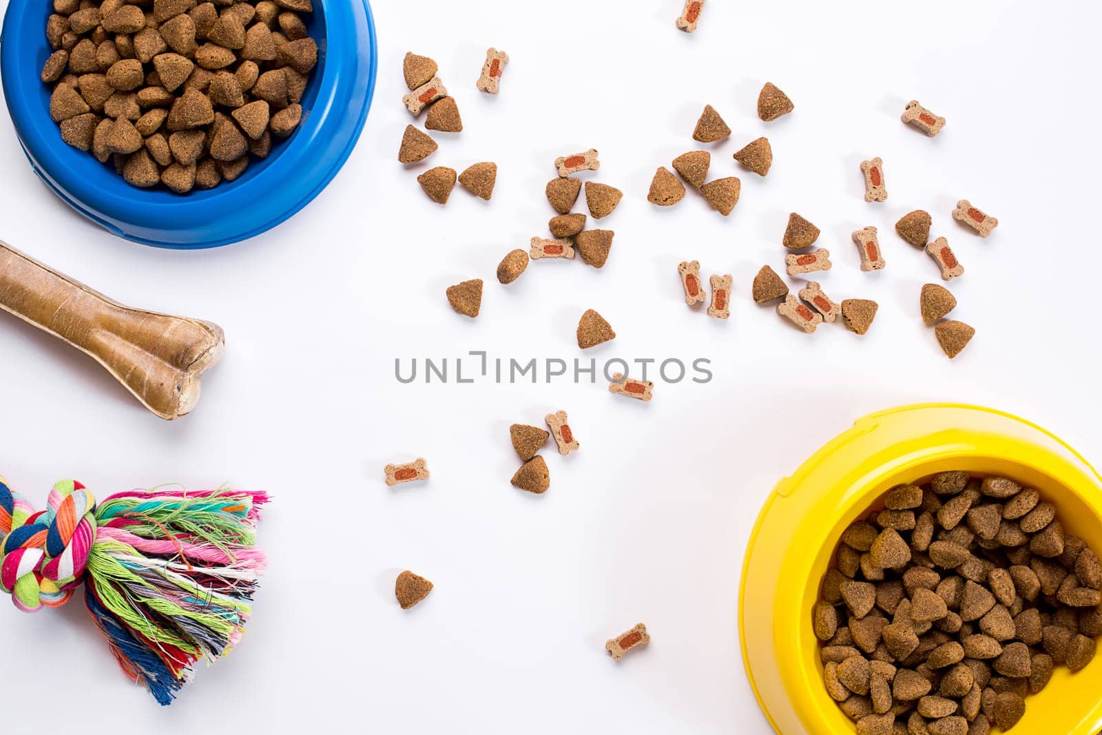 dry pet food in bowl and toys for dogs on white background top view. Still life. Copy space