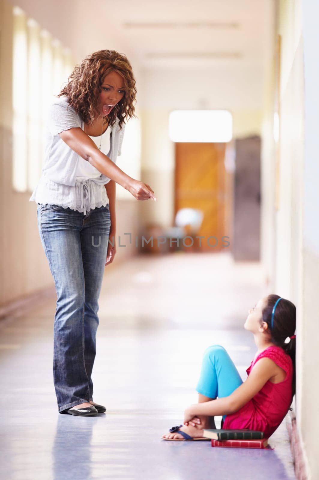 School, teacher and shouting at child student for bad behaviour, problem or lesson. Angry black woman pointing and scolding girl for discipline, attitude or education fail in building hallway by YuriArcurs